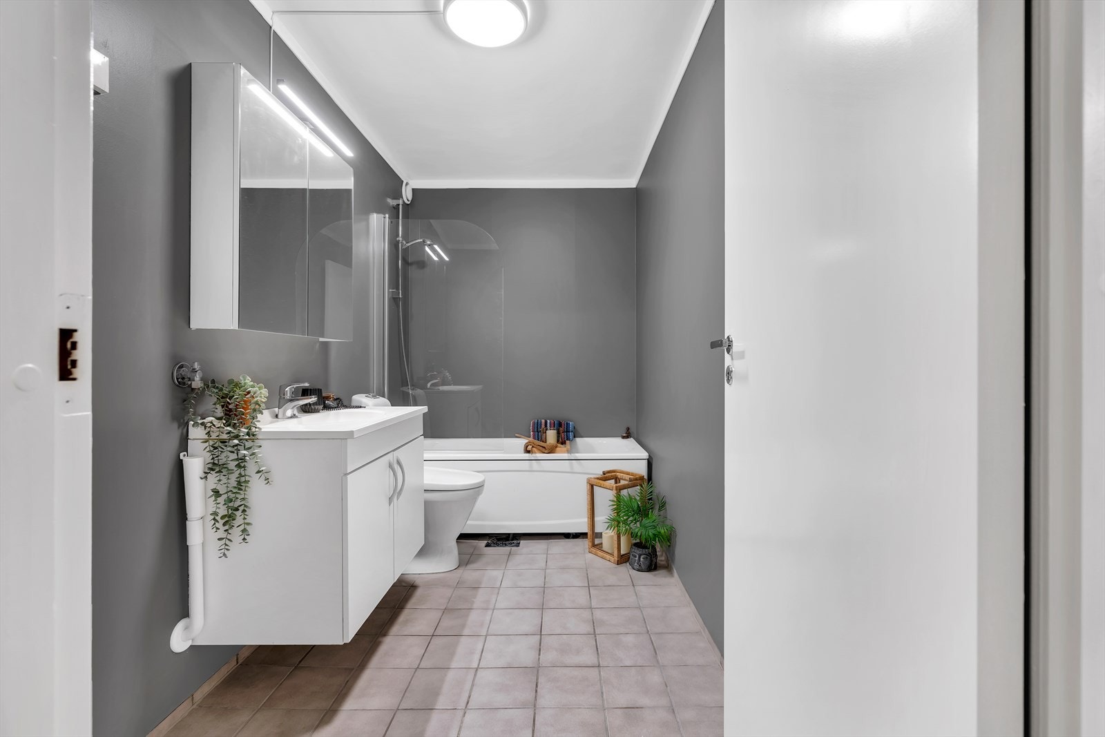 Badet er delikat innredet med gulvvarme, lyse gulvfliser og gråmalte vegger. Galleribilde