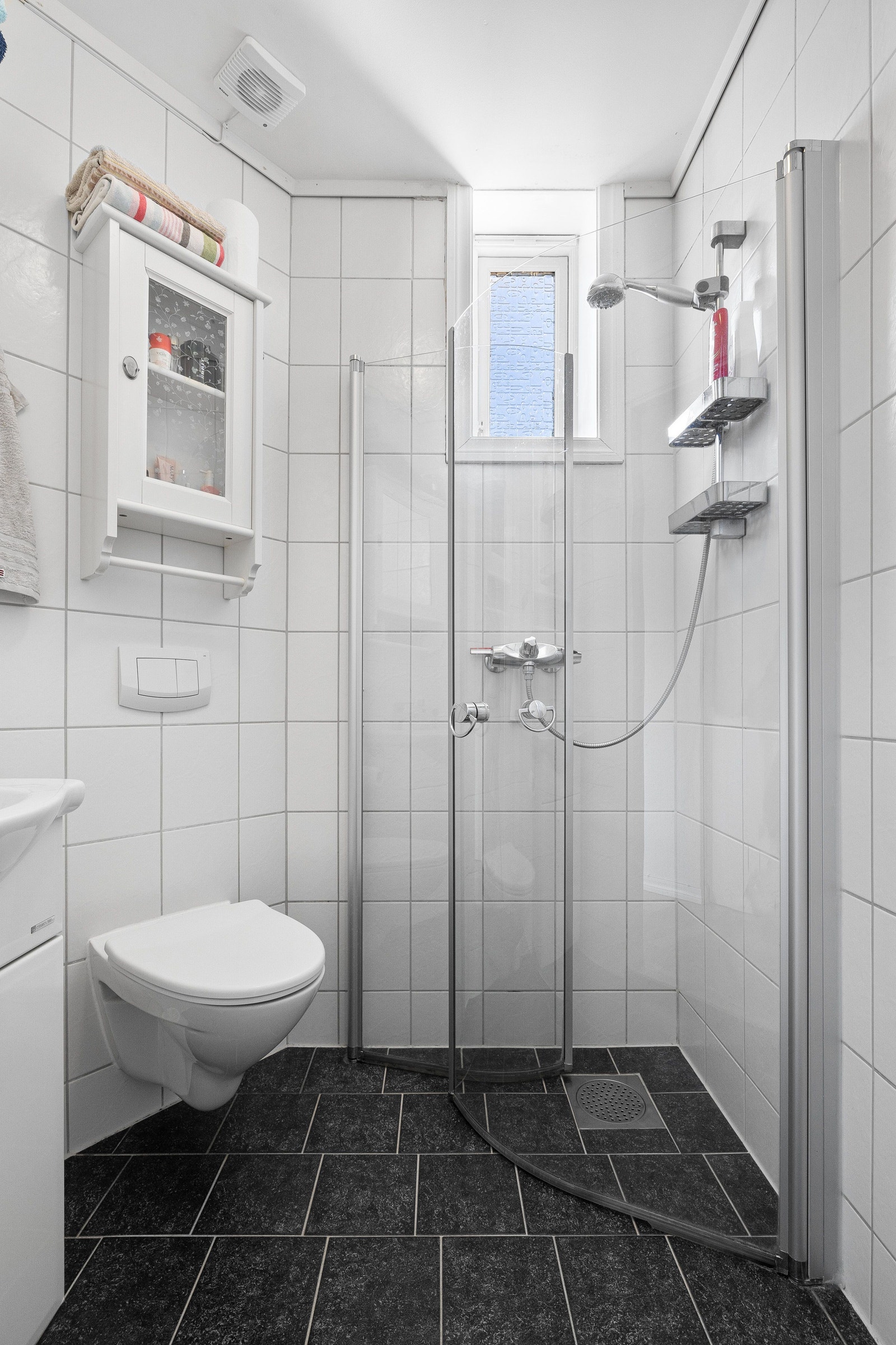 Bad med vegghengt toalett, dusj og servant med innredning Galleribilde