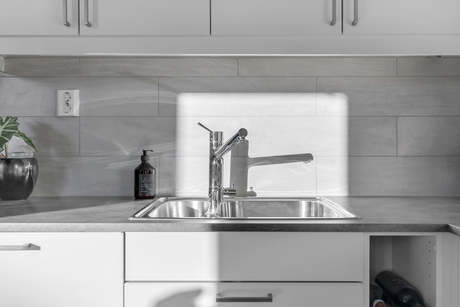 Delikat kjøkkeninnredning fra Sigdal med lyse slette fronter. Fliser på vegg over kjøkkenbenk. Galleribilde