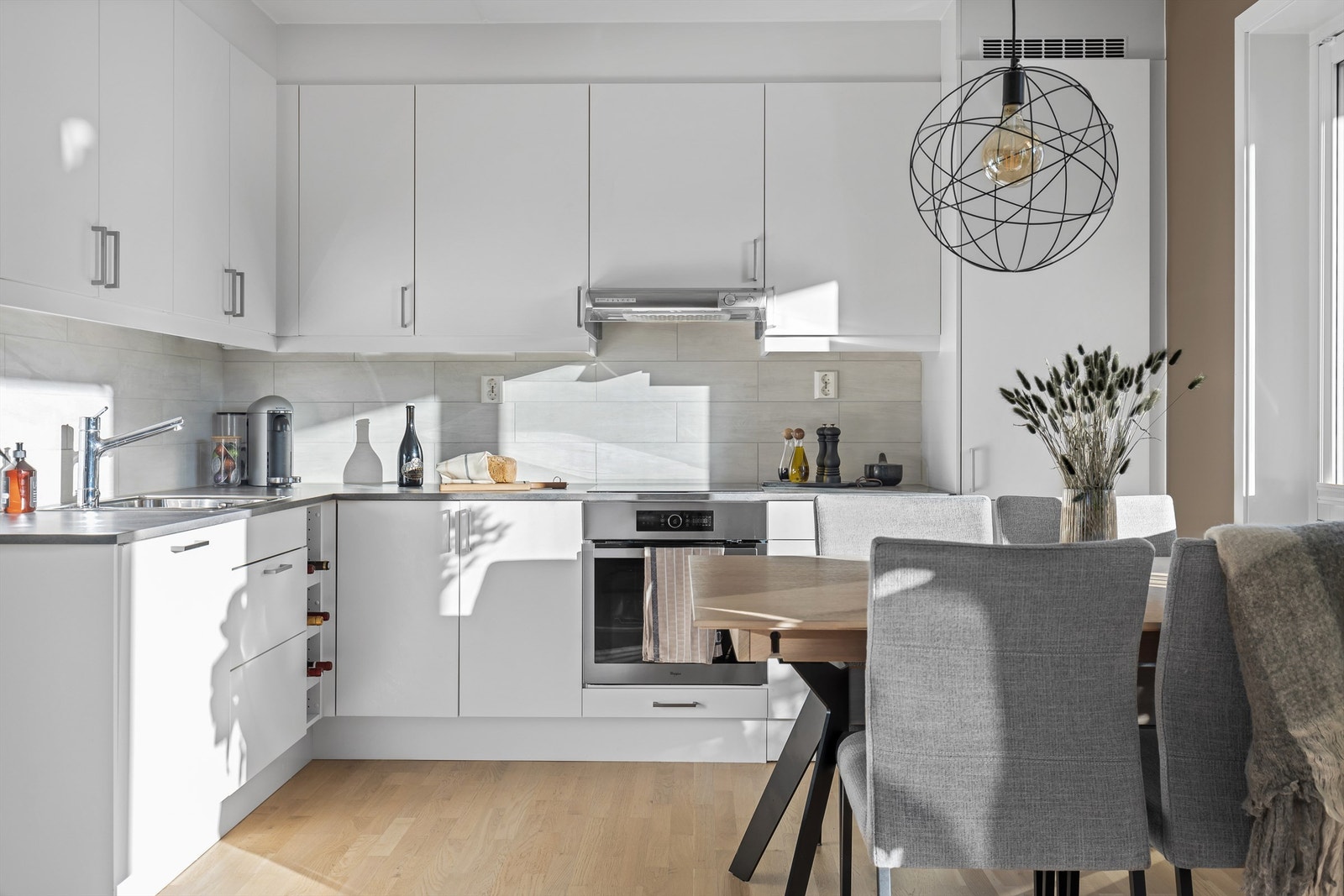 Delikat kjøkkeninnredning fra Sigdal med lyse slette fronter. Benkeplate av laminat. Fliser på vegg over kjøkkenbenk. Galleribilde