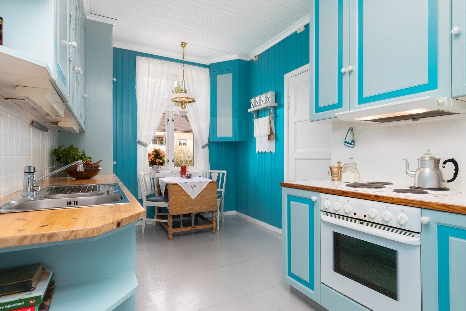 Kjøkkenet har rikelig med skap- og benkeplass som gjør matlagingen til en lek. Her har man en praktisk takhøy innredning, malt i sjarmerende blåfarger som gir en god atmosfære. Galleribilde