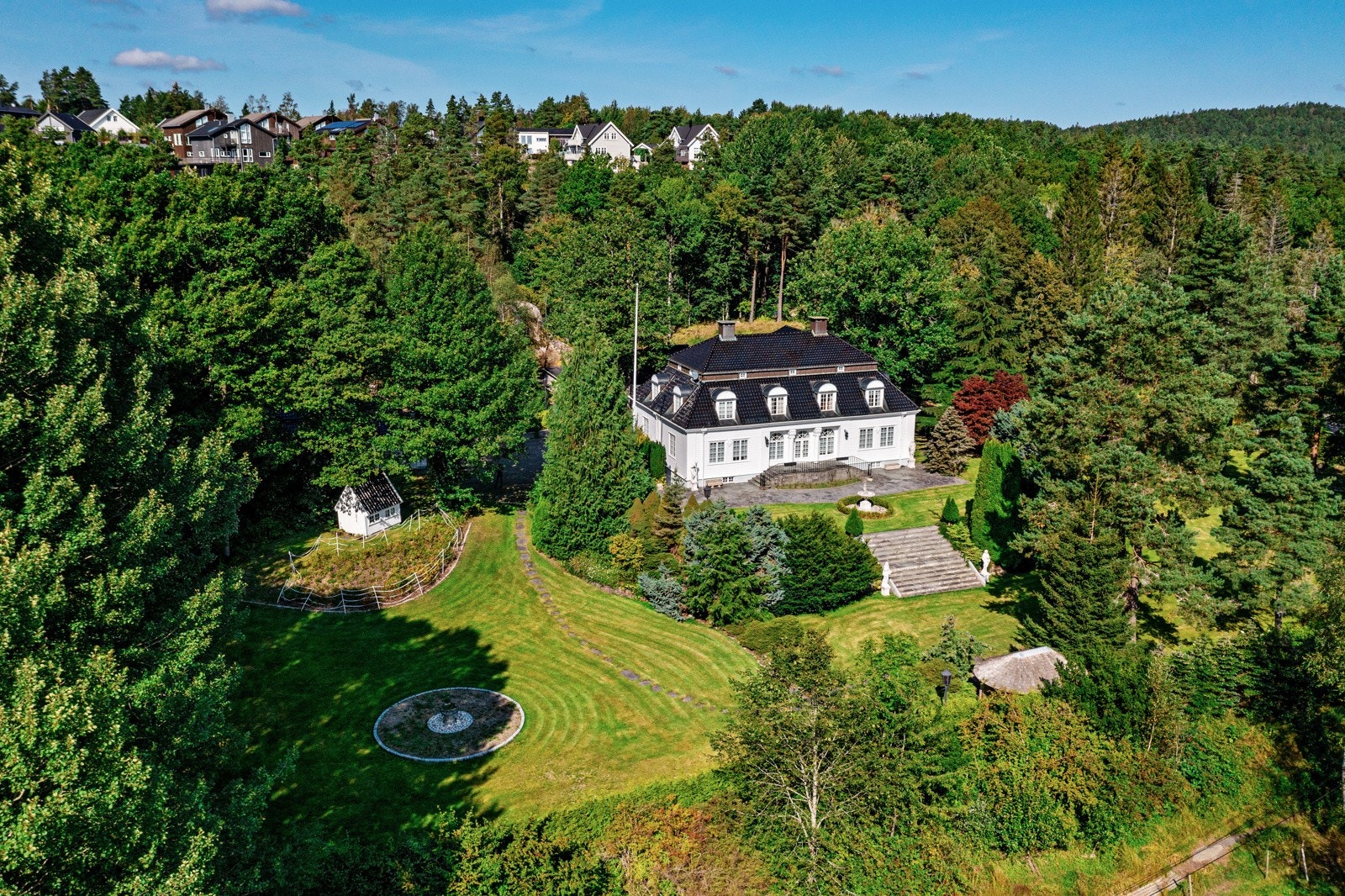 Dronefoto over del av eiendommen med huset i midten Galleribilde