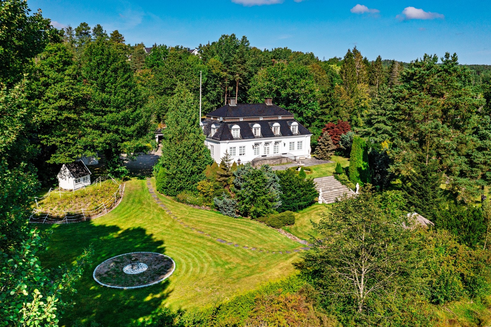 Dronefoto over del av eiendommen med det herskapelige huset i midten Galleribilde
