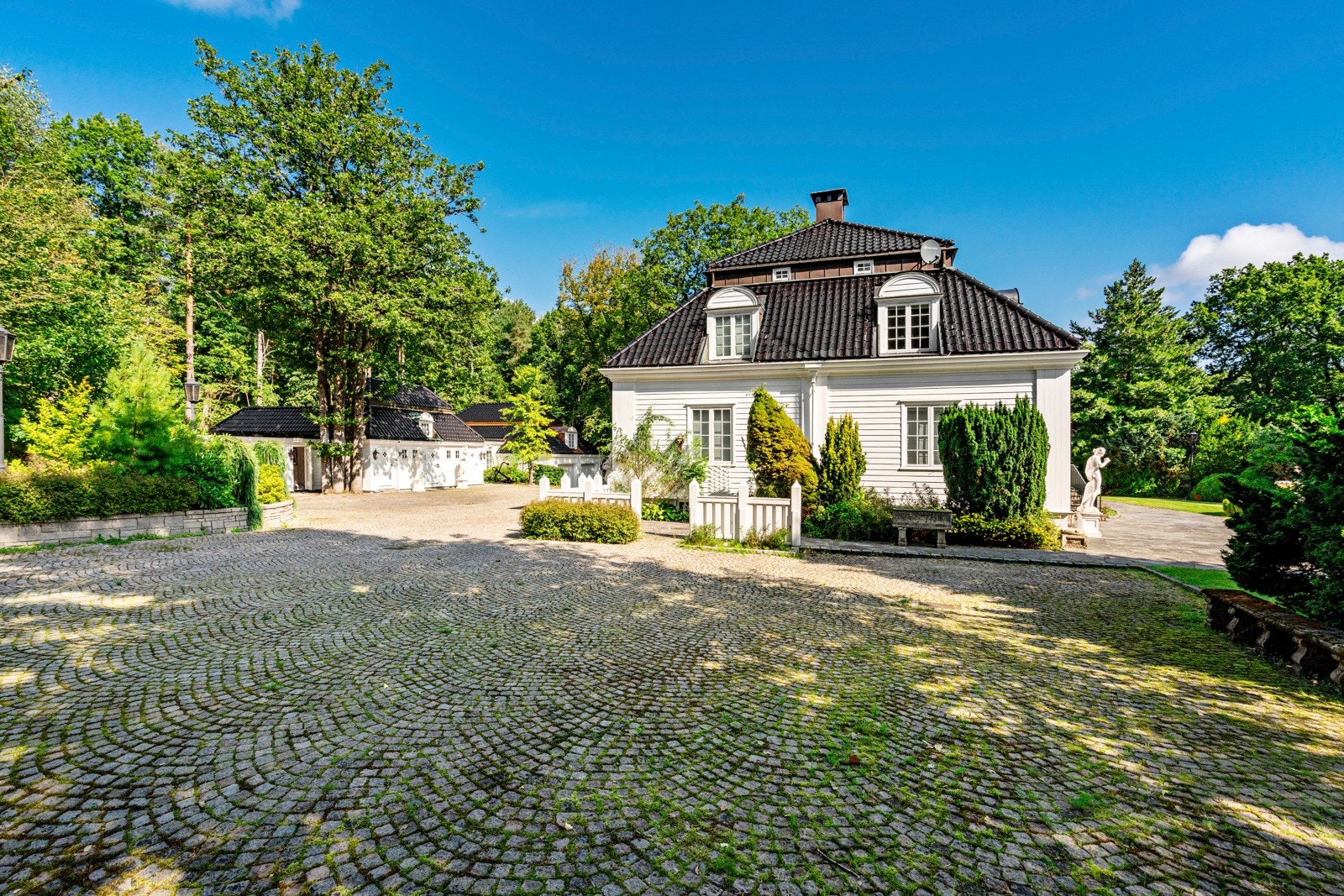Stor gårdsplass mellom huset og garasjebygget/uthuset Galleribilde