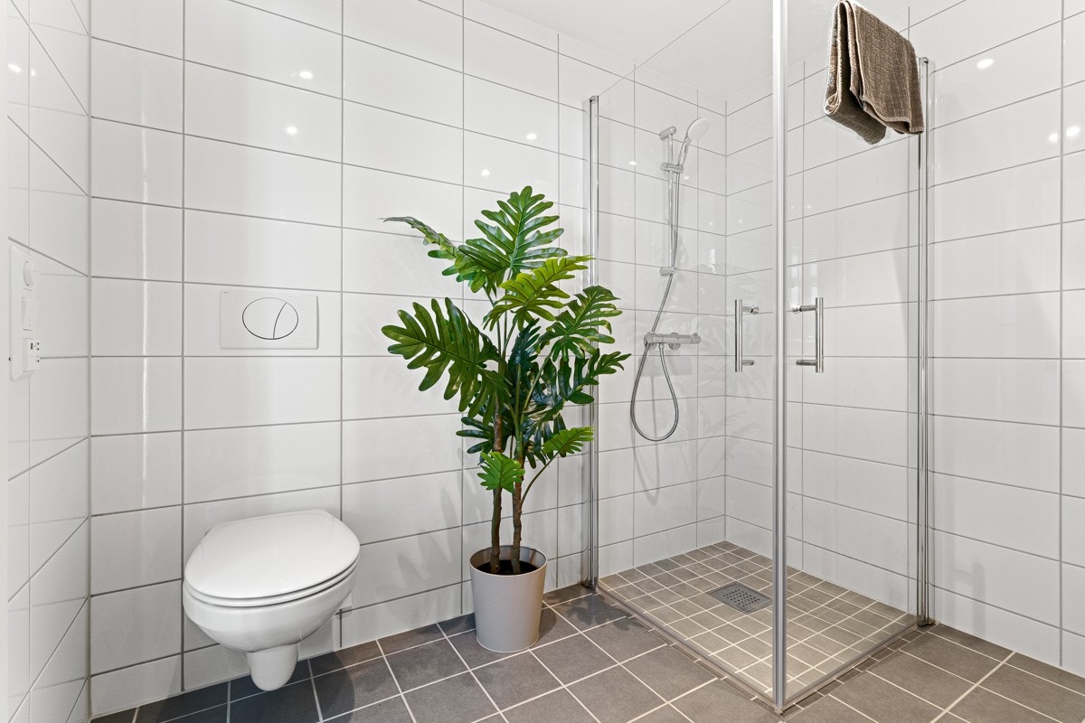 Det er varme i gulvet og utstyr som innfellbare dusjdører, mekanisk avtrekk, opplegg for vaskemaskin, servant, servantskap og veggmontert wc Galleribilde