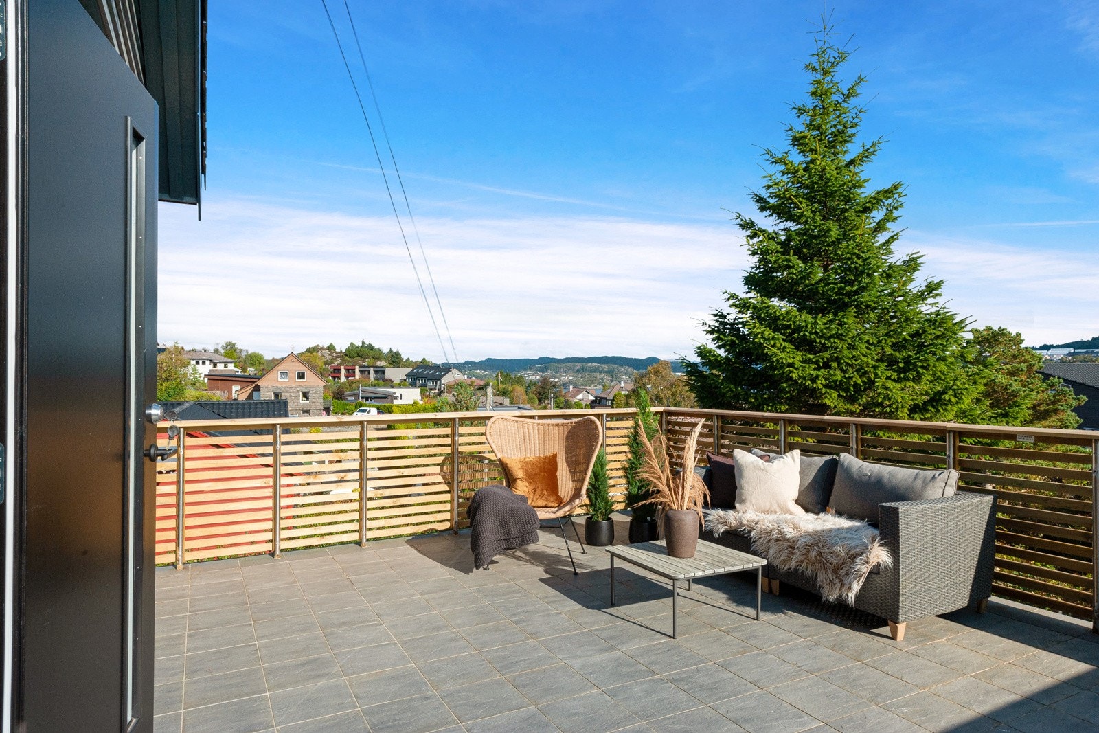 Stor terrasse med fliselagt dekke ved husets hovedinngang. Galleribilde