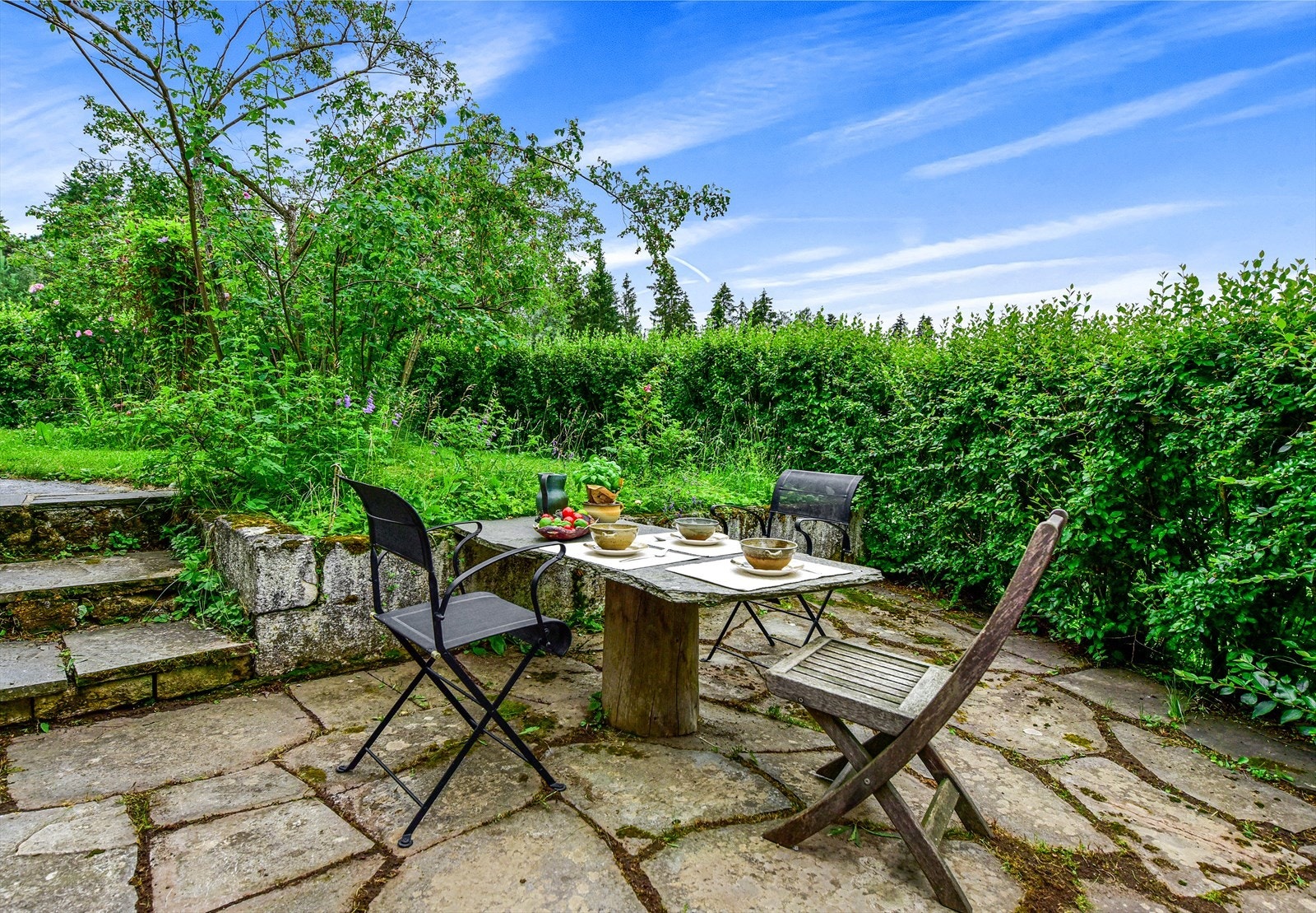 Eiendommen har også hellelagte uteplasser: her er det bare å forflytte seg etter vær og vind. Galleribilde