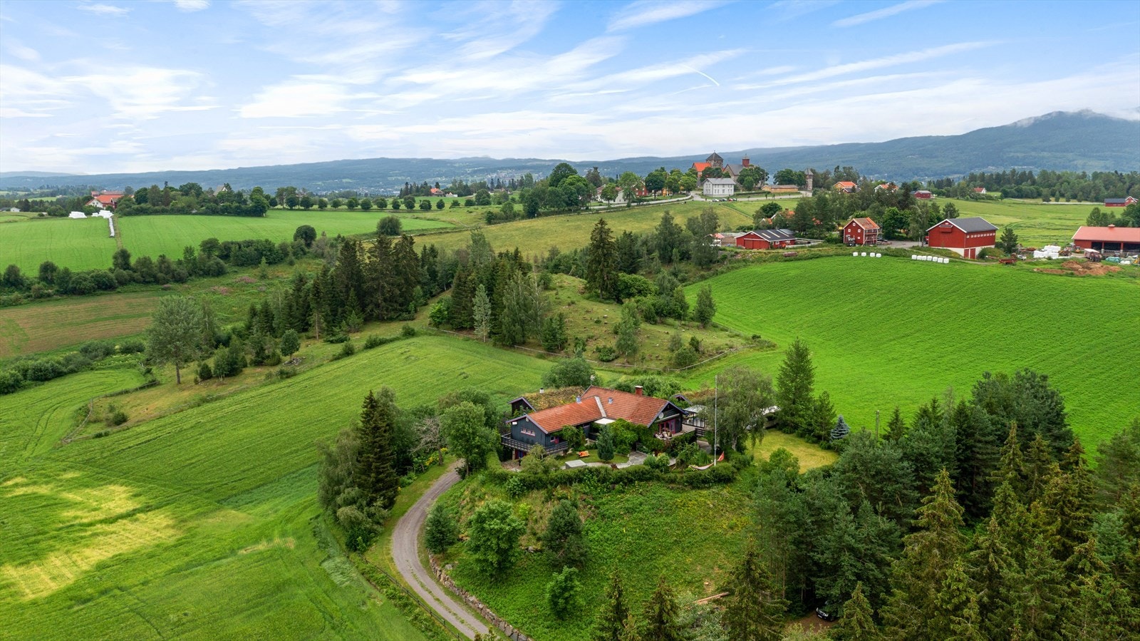 Eiendommen ligger fritt og usjenert til i Helgumsdalen, omgitt av gårdsbruk og dyrket mark. I bakgrunnen ser vi Granavollen og Søsterkirkene. Galleribilde