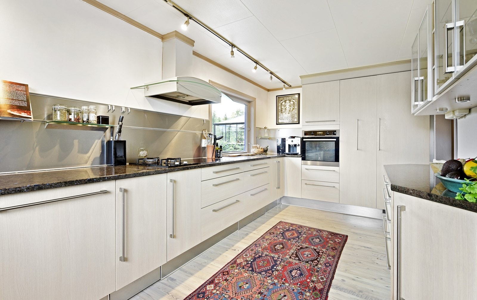 Kjøkkenet er av nyere dato med glatte skapfronter og benketopper i stein. Parkett på gulvet og lysskinner i taket. Store vinduer gir godt arbeidslys i rommet. Galleribilde