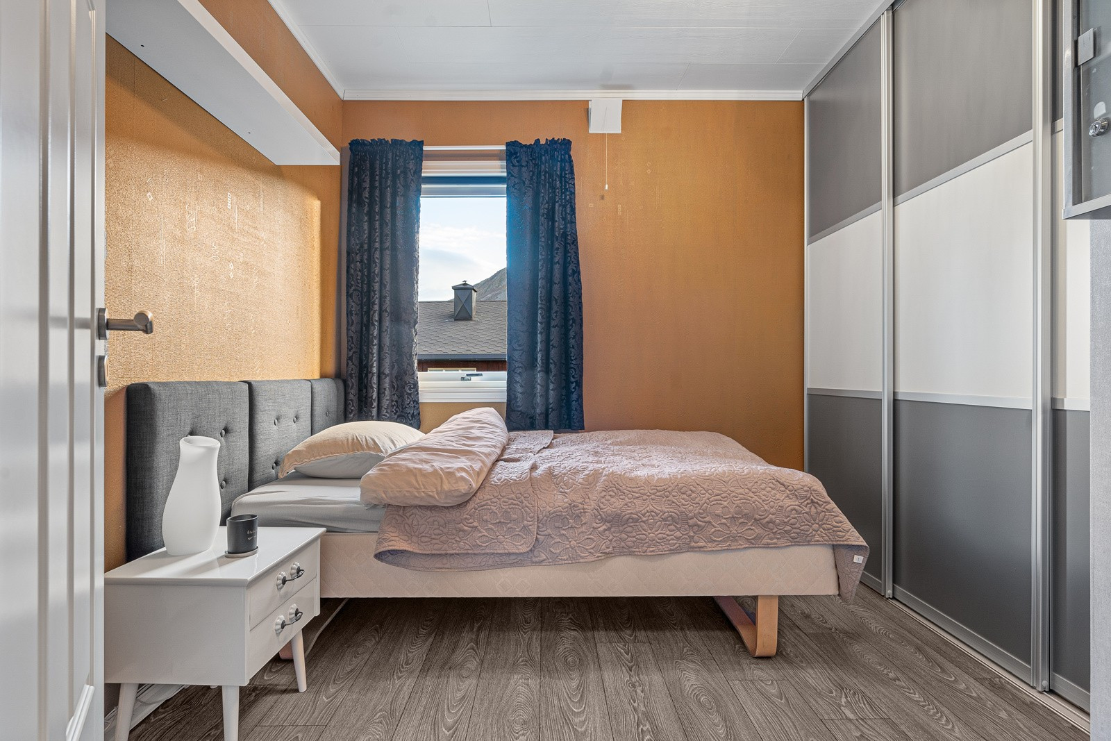 Soverom 2 har en stilig oransje farge på veggen og stor skyvedørsgarderobe