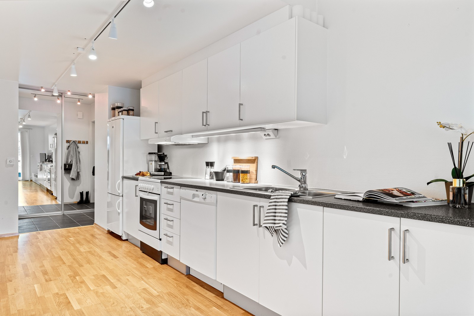 Videre inn i boligen kommer du til kjøkkenet. Kjøkkenet fremstår moderne med god skap- og benkeplass som gir rikelig med lagringsplass og praktiske arbeidsforhold.
