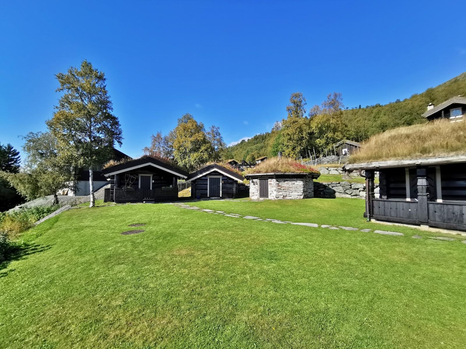 I tillegg til hovedhytte med carport og tilbygget anneks, har eiendommen to anneks i tømmer og en røykstue i skifer Galleribilde