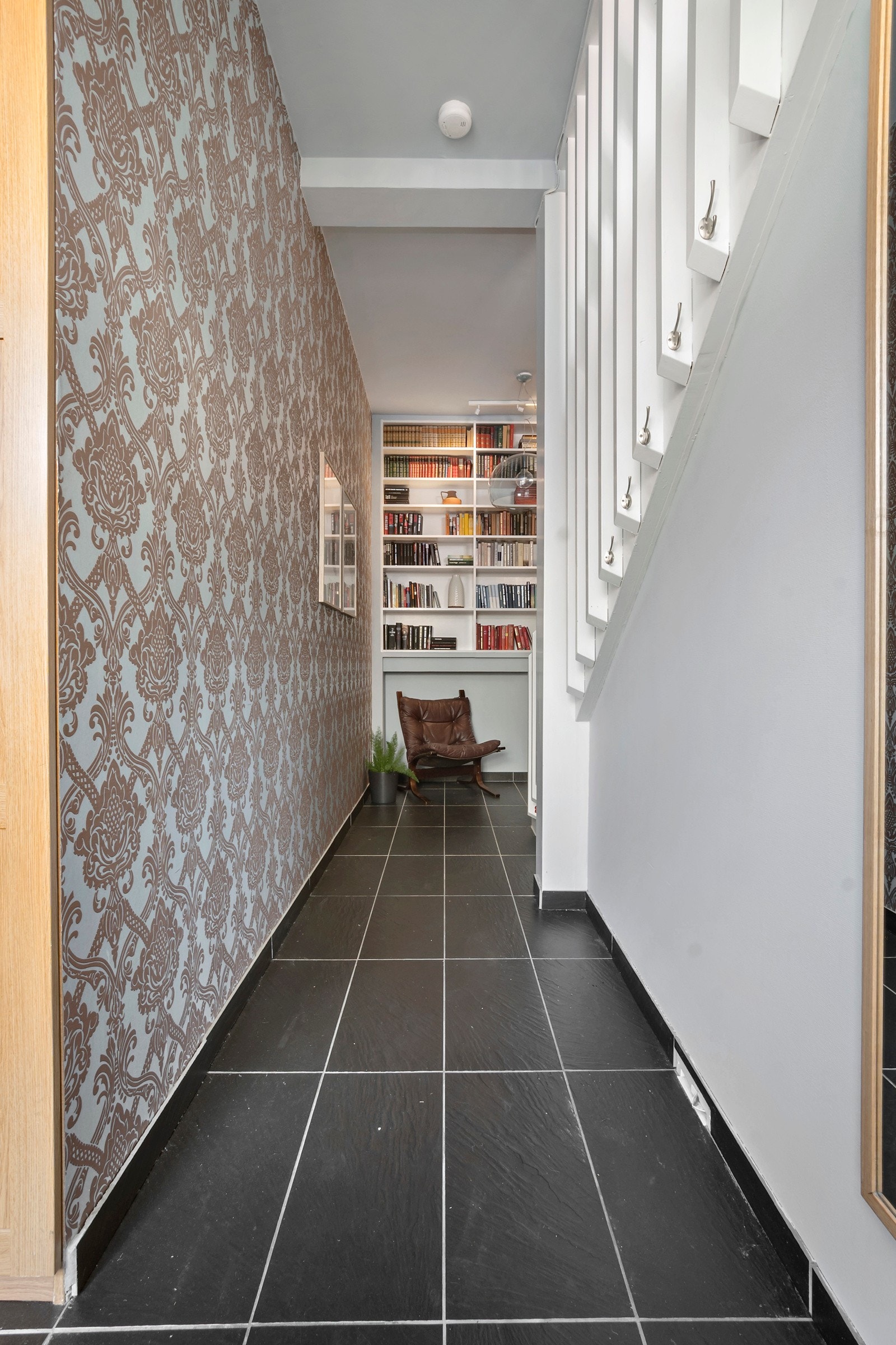 Det er også mulighet for oppheng av yttertøy på kroker som er fastmontert i trappen. Det er også plassbygde hylleløsninger på vegg som vender mot praktikantdel. Galleribilde