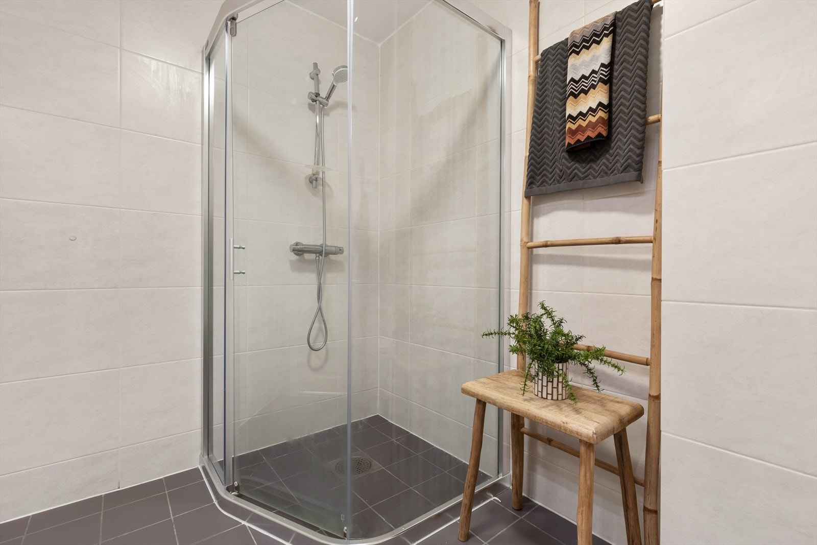 Dusjhjørne med termostatbatteri og dusjvegger i herdet glass, veggmontert toalett, helstøpt servant med ett-greps bl.batteri og servantskap. Galleribilde