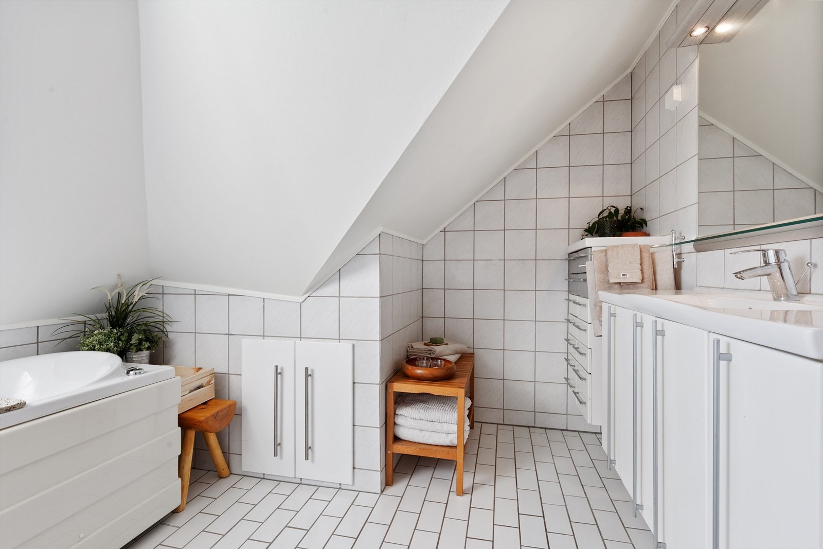 Innredningen består av badekar med dyser, toalett, servant med skapinnredning og speil med belysning. Galleribilde