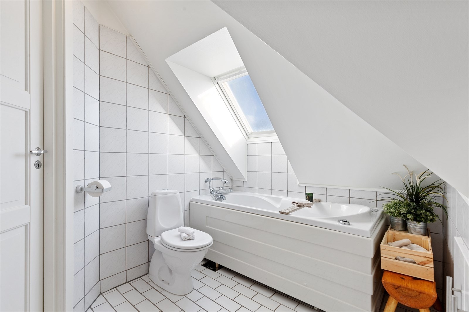 Lyst baderom med takvindu. Gulv- og veggflatene består av tidløse fliser. Galleribilde