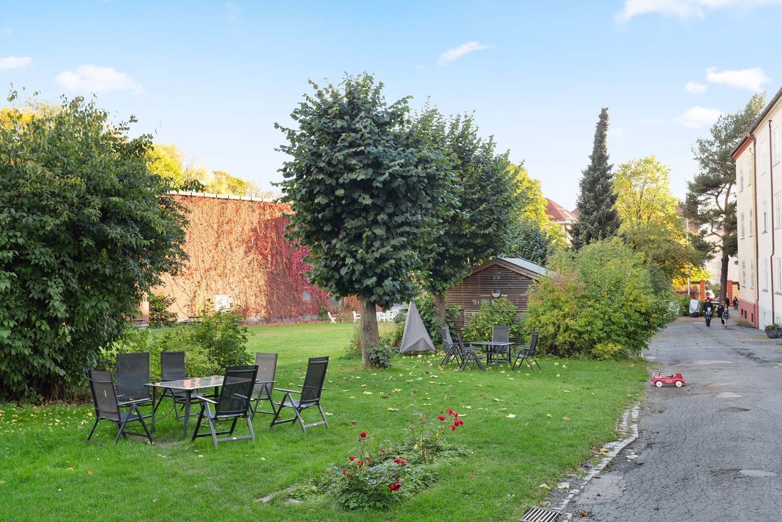 Pent opparbeidet fellesareal i kvartalbebyggelse med asfalterte adkomstveier/ plasser, steinbelagte arealer, gressplen, beplantning, trær, sittegrupper, lekeapparater m.m. Galleribilde