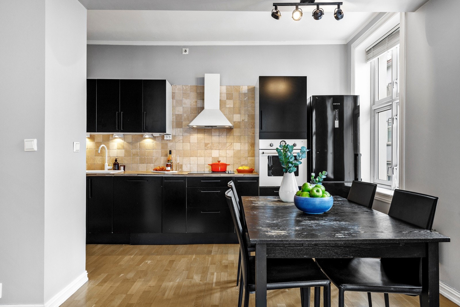 Kjøkkenet fremstår med innredning fra IKEA med profilerte fronter, laminat benkeplate, fliser over benkeplaten. Integrerte hvitevarer som komfyr, platetopp og oppvaskmaskin. Galleribilde