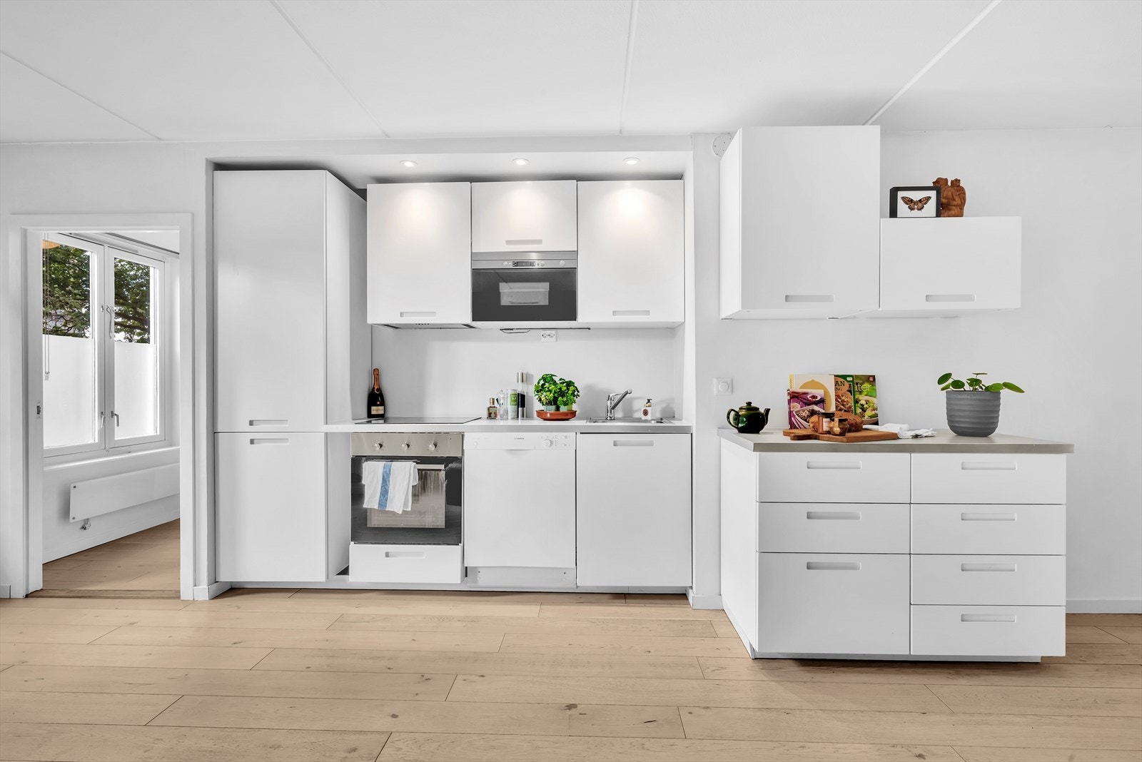 Flott kjøkken bestående av glatte fronter. Laminat benkeplate med nedfelt kum i rustfritt stål. Kjøkken flyttet til stue uten byggemelding. Galleribilde