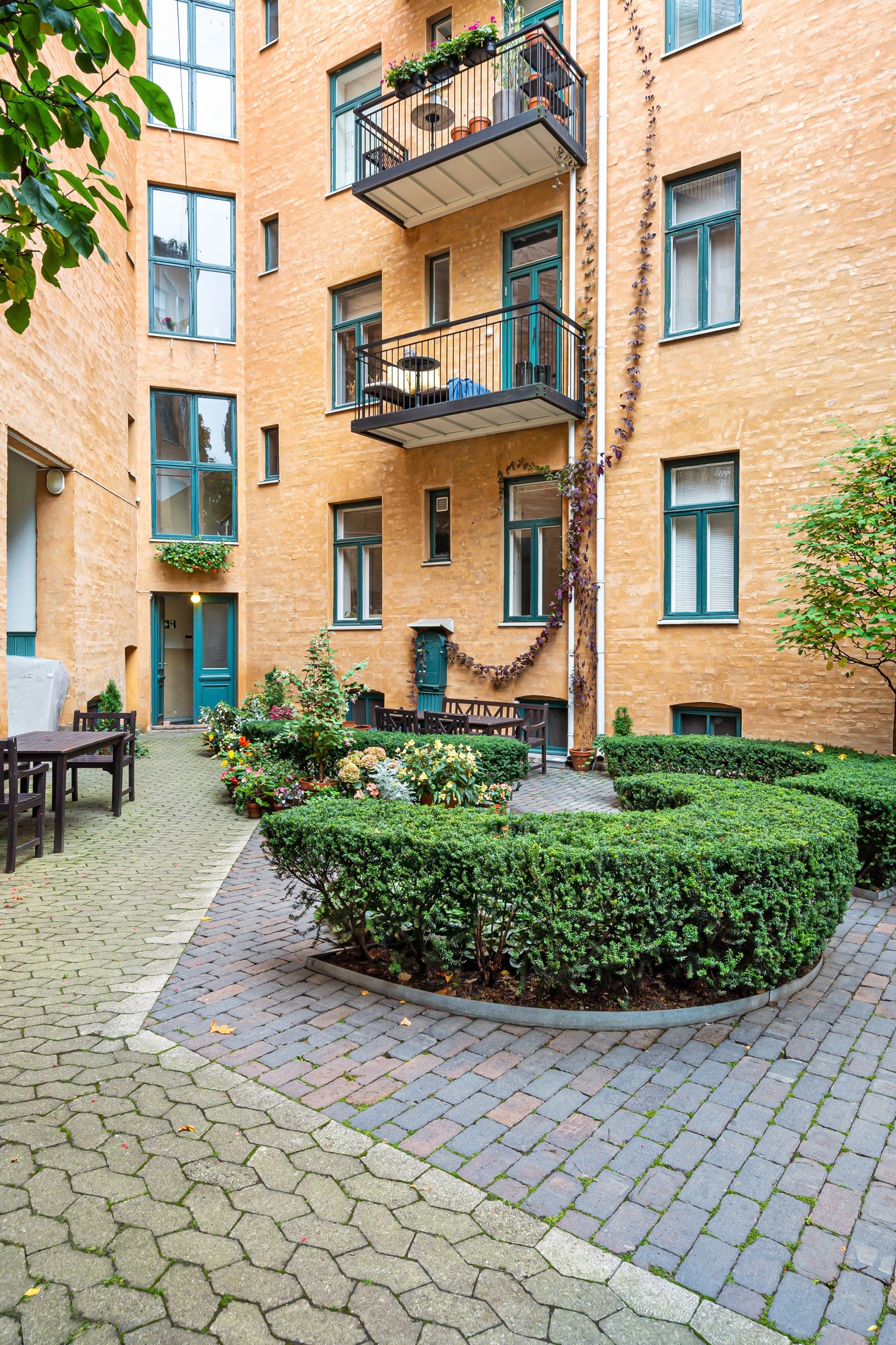 Gårdsrommet er pent opparbeidet med belegningsstein og trimmede busker som avgrenser soner for sittegrupper sommerstid. Galleribilde