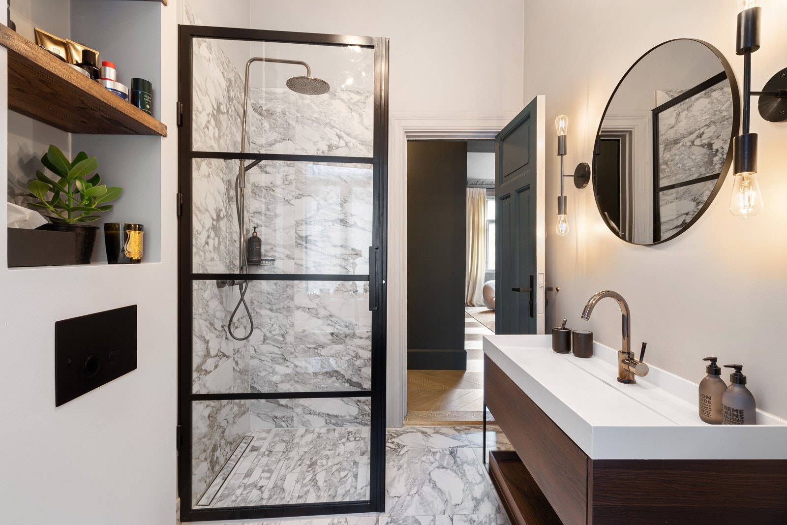 Rommet har fine nisjehyller i veggen over vegghengt toalett og speil med sidebelysning. Servantseksjonen har heldekkende vask, innebygget bluetooth og blandebatteri fra Tapwell i sort crome. Dusjhjørnet er rammet inn med glass med sortlakkerte jernrammer. Galleribilde