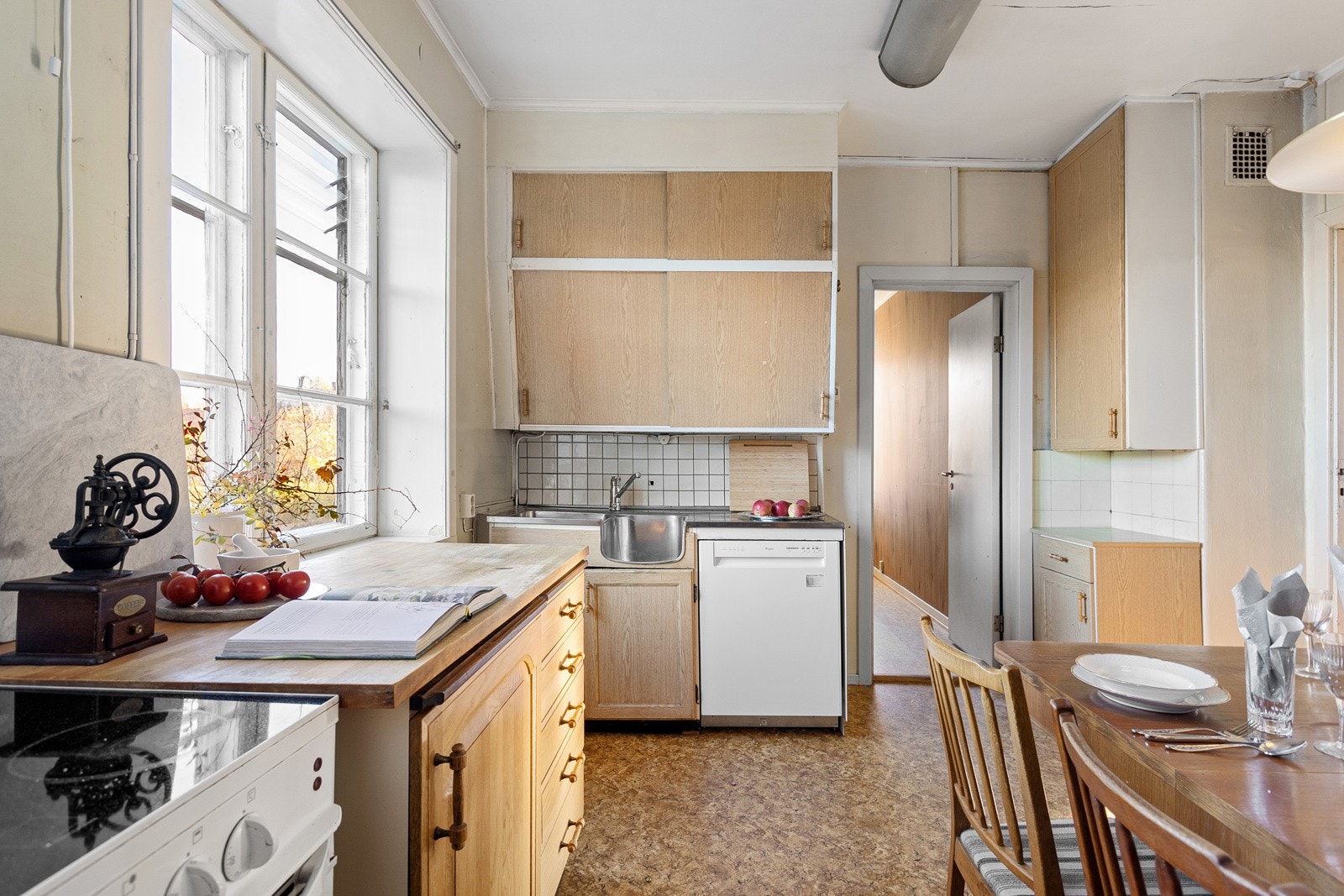 Eldre profilert kjøkkeninnredning, rustfritt benkebeslag med kum og fliser over benk. Galleribilde