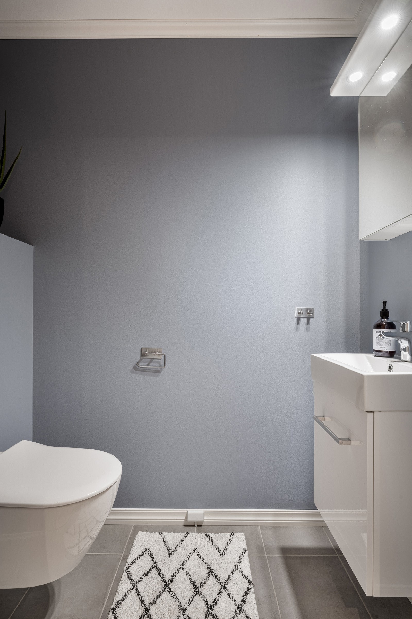 WC-rom i første etasje med fliser på gulv og platekledning malt i en behagelig grålig blå farge Galleribilde