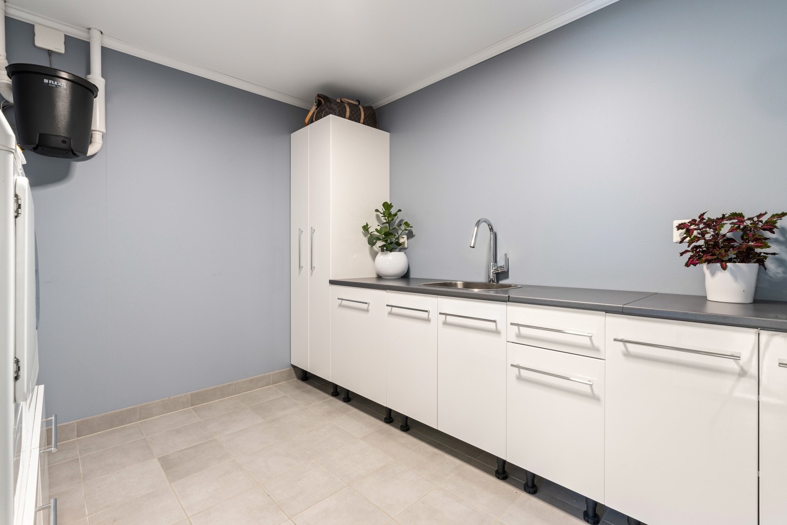 Stort vaskerom med fliser på gulv og mye oppbevaring Galleribilde