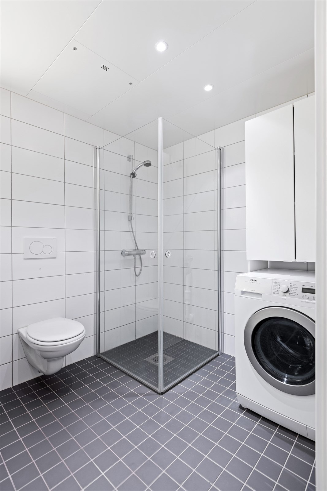 Badet har gulvvarme og downlights, i tillegg til vegghengt toalett, dusjhjørne og opplegg til vaskemaskin. Galleribilde