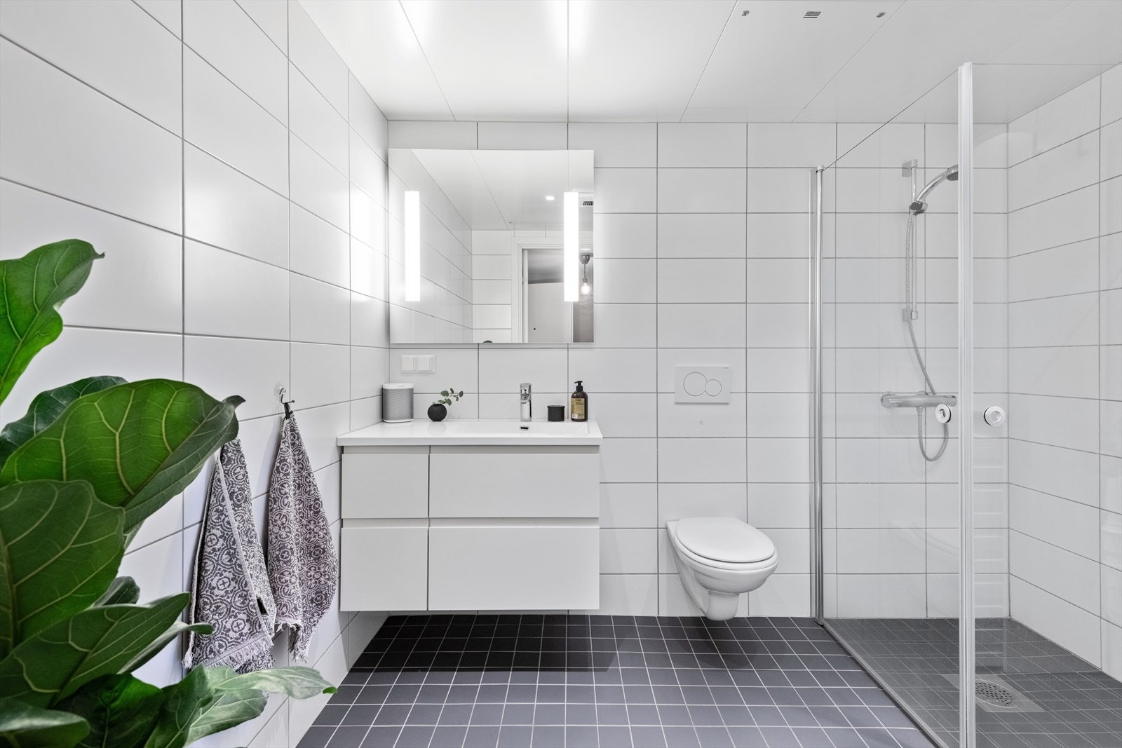 Badet har godt armslag og er stilrent flislagt i grått og hvitt. Baderomsinnredningen er fra HTH. Galleribilde