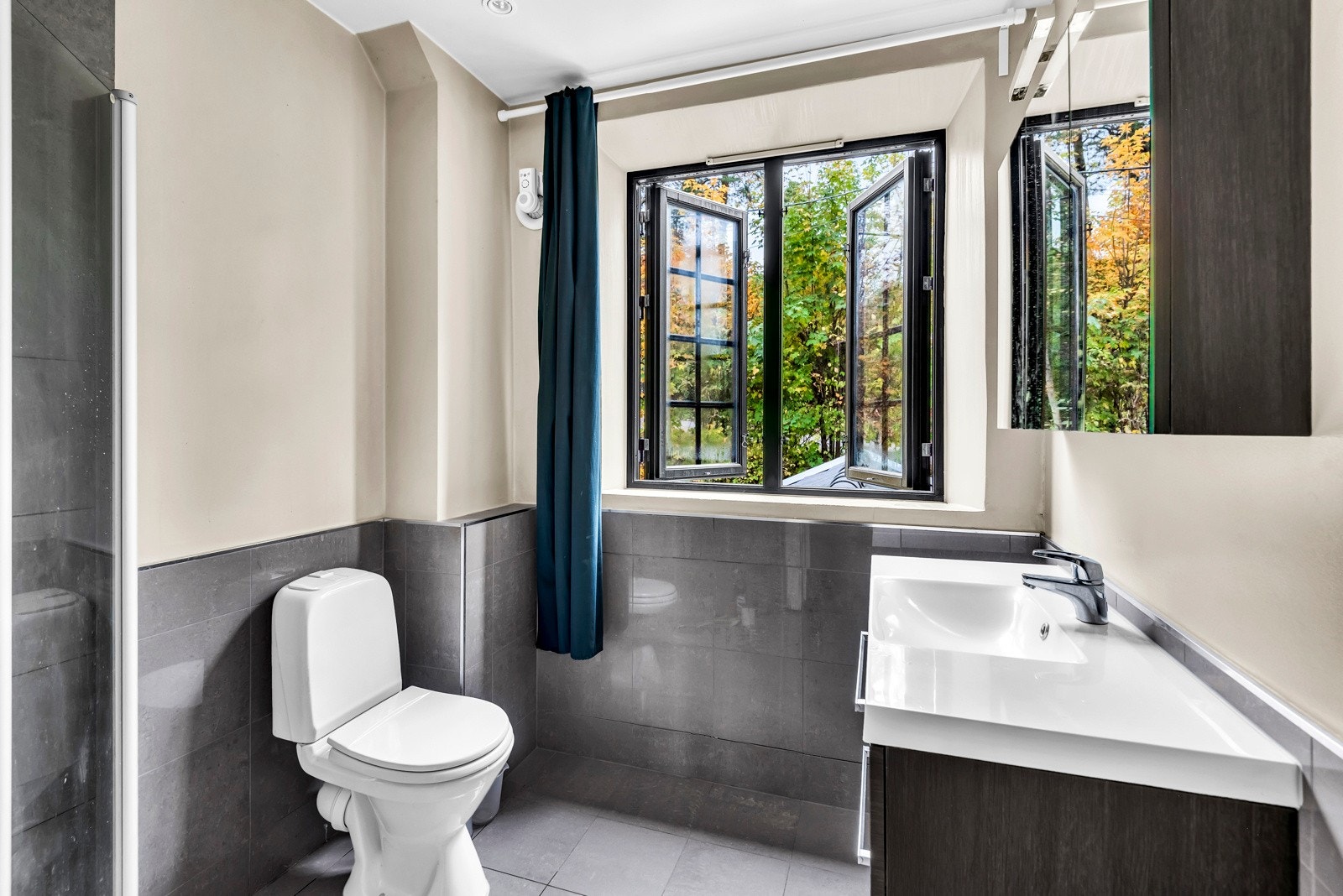 Bad III - Badet er innredet med servant med over- og underskap, dusj, samt toalett Galleribilde