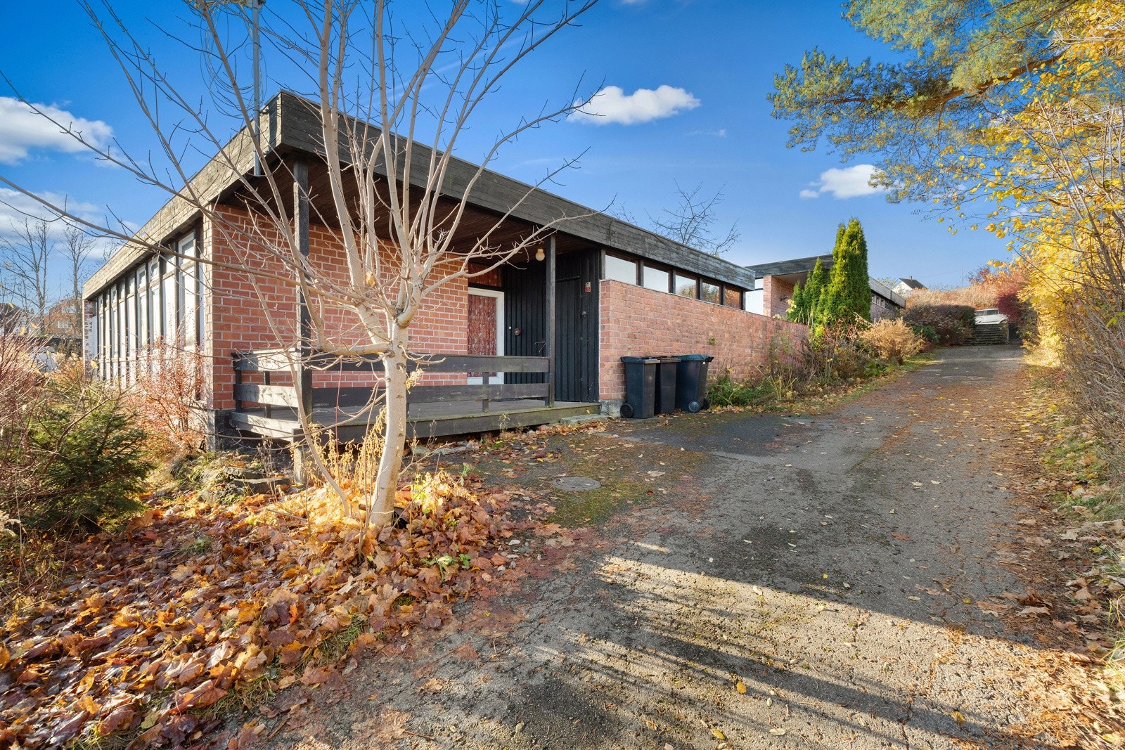 Boligen har adkomst fra et overbygget inngangsparti med terrasse og ytterdør i glass. Galleribilde