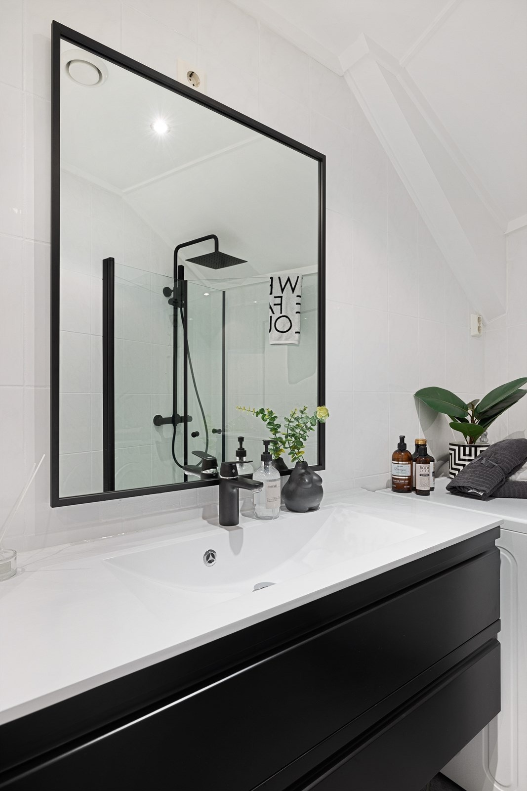 Vegghengt servantskap med glatte fronter i sort utførelse. Ovenpåliggende servant av kompositt med ett-greps armatur. Speil på vegg over servant Galleribilde