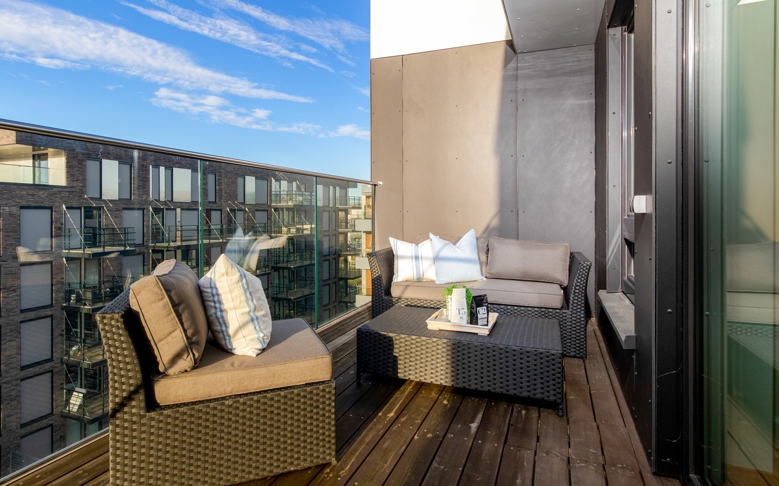 Balkongen vender ut mot velholdte fellesareal som har støpte gangareal blant gressplen, trær og bed. Galleribilde