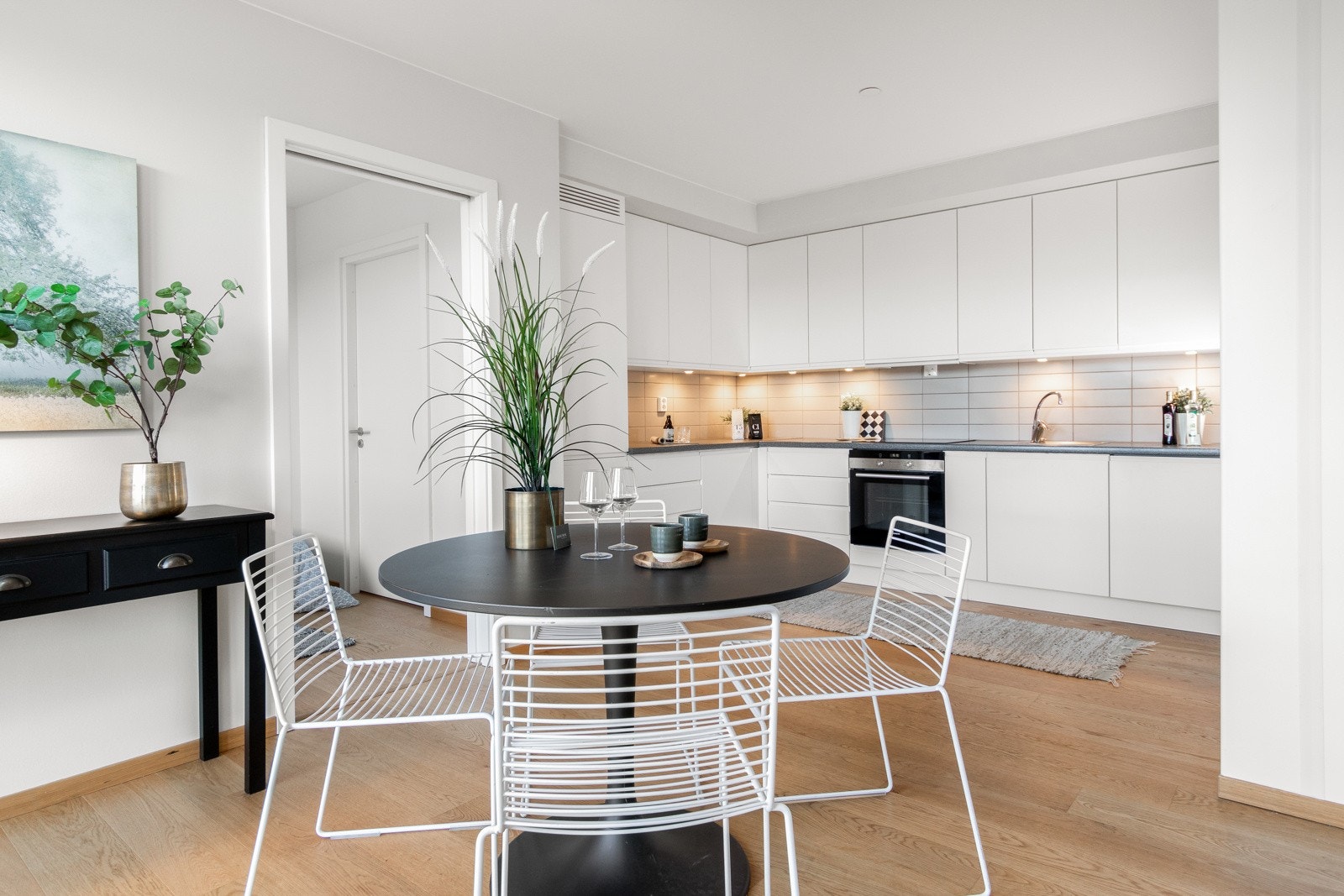 Kjøkkenet har takoppforede overskap og hvite, glatte fronter for et moderne uttrykk. Benkeplaten er mørk og har nedfelt benkebeslag. Galleribilde