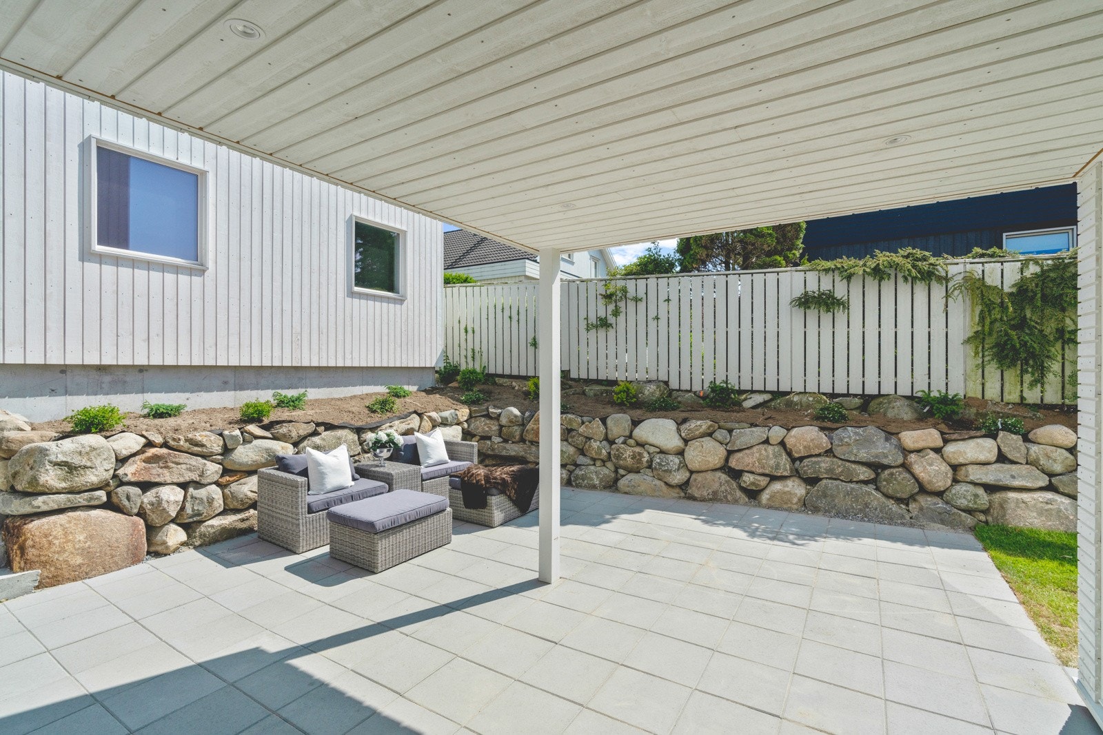 Terrassen ved inngangen ligger lunt inntil stablet mur og husvegg. Galleribilde