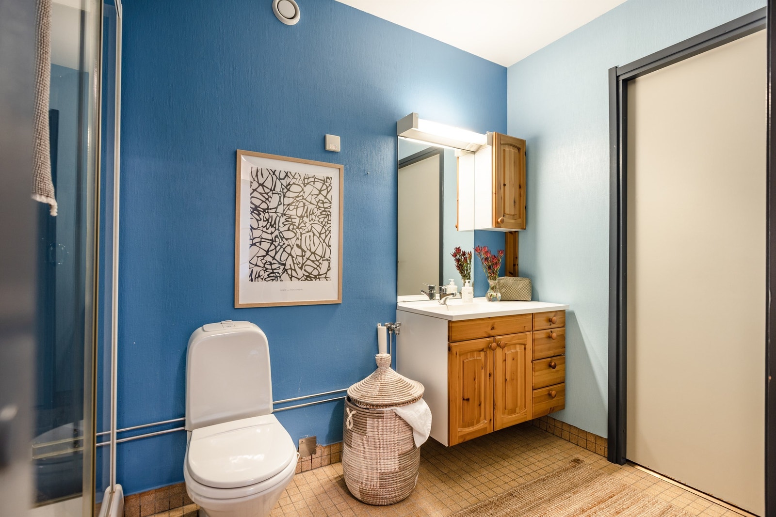 Baderom med servant, speil, klosett, dusjkabinett og opplegg til vaskemaskin. Galleribilde