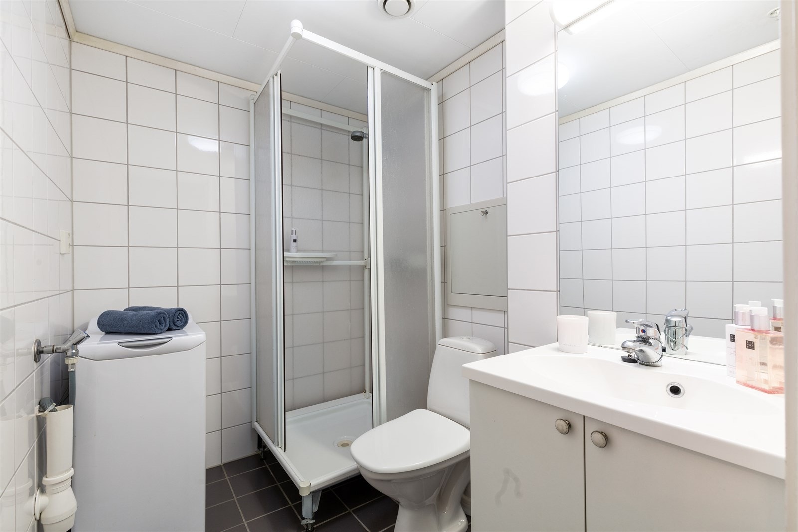 Flislagt bad med varmekabler, som er videre utstyrt med heldekkende servant, wc, dusjkabinett og opplegg for vaskemaskin Galleribilde