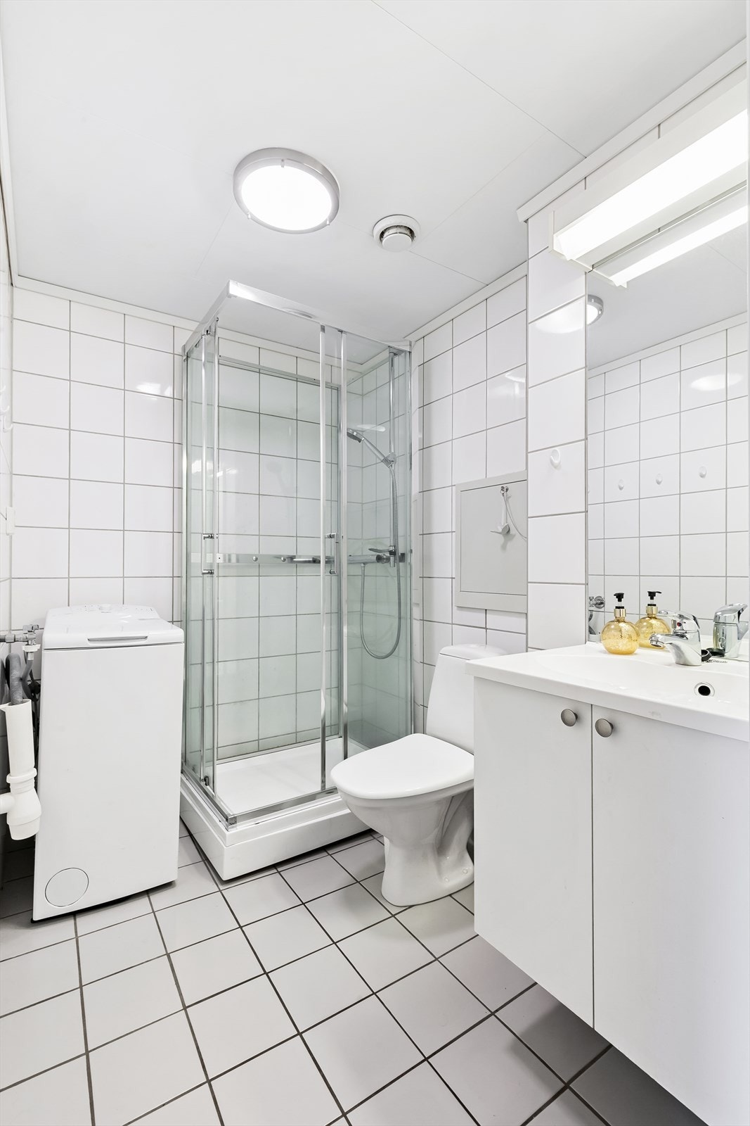 Pent flislagt baderom fra byggeår med gulvvarme. Baderomsinnredning med folierte glatte fronter samt heldekkende servant. Galleribilde