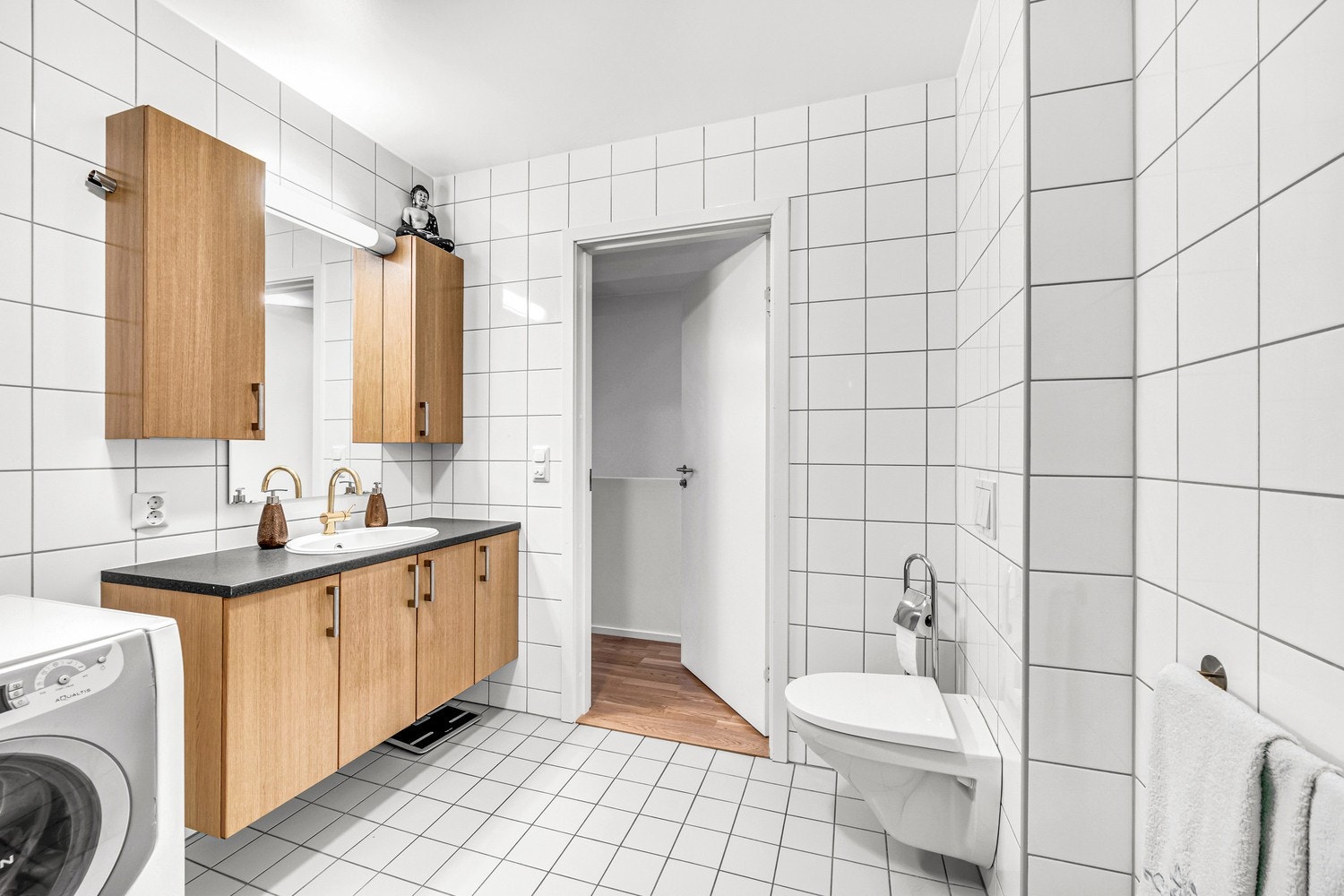 Pent, flislagt bad med åpen dusjplass, vegghengt WC og baderomsinnredning med underskap og speil med sideskap. Galleribilde