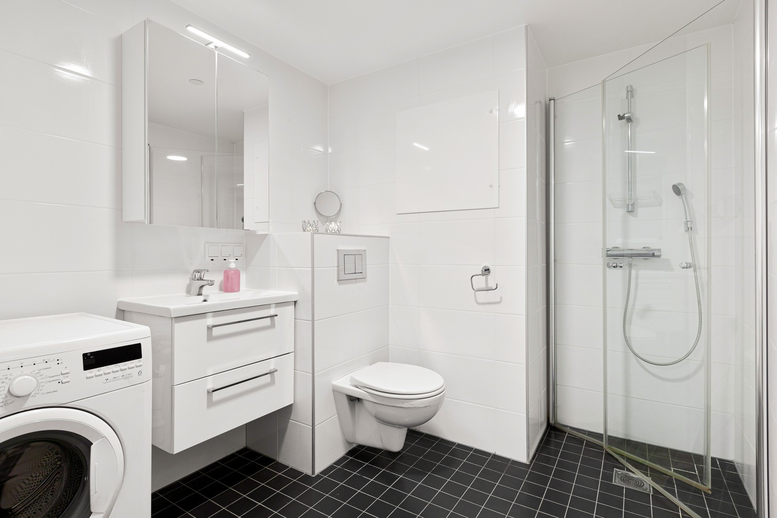 Innbydende baderom med varmekabler i gulv, plassbesparende innredning og opplegg for vaskemaskin/ tørketrommel