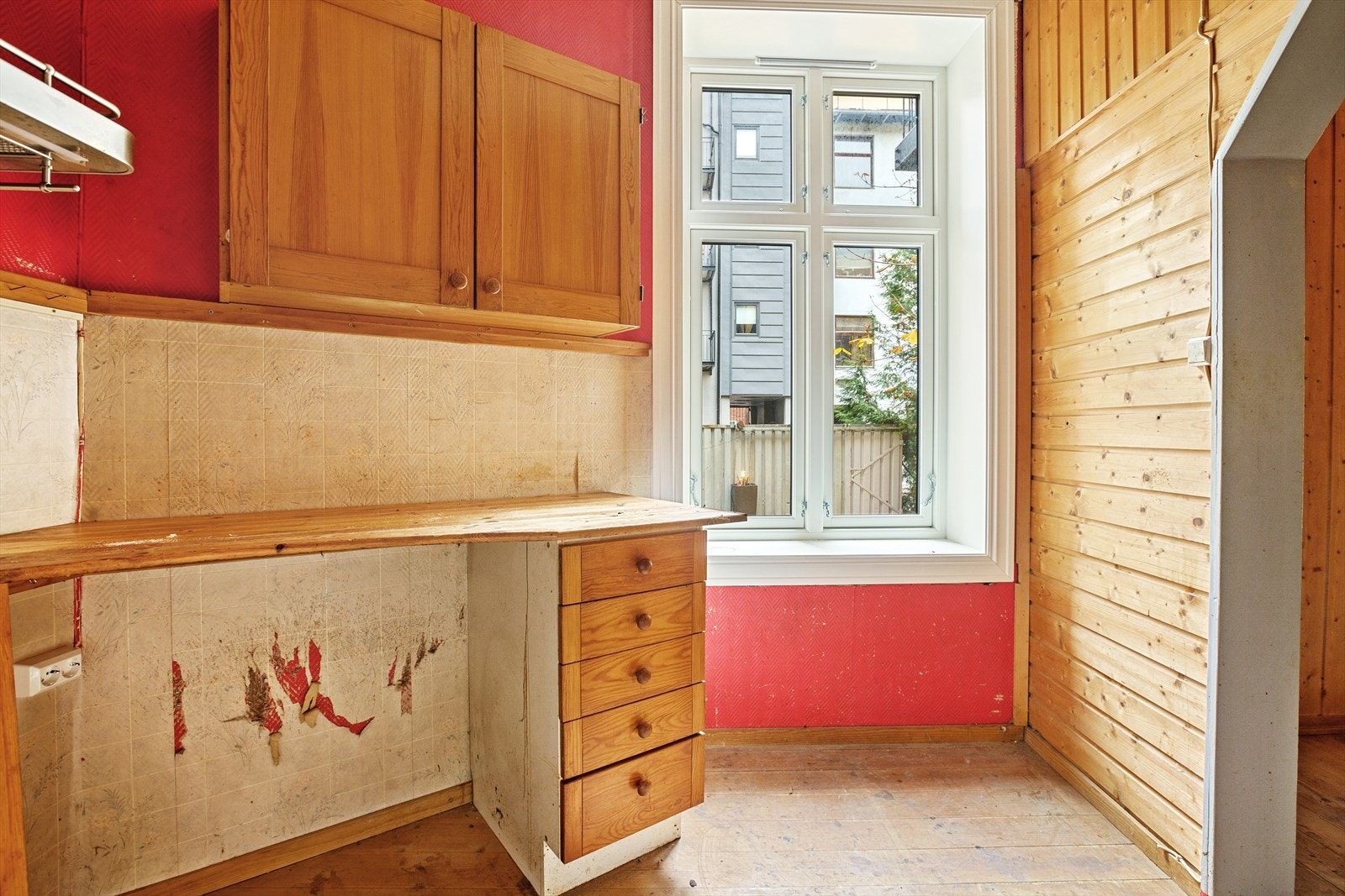 Delvis åpent kjøkken med kjøkkeninnredning fra 1960-årene med profilerte, malte fronter, heldekkende rustfri oppvaskkum samt laminat plate og slitt benkeplate i heltre. Ventilatoren er med kullfilter. Galleribilde