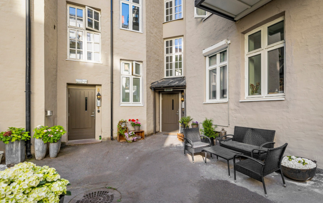 Pent opparbeidet gårdsrom med asfalt og sykkelparkering samt noe beplantning. Galleribilde