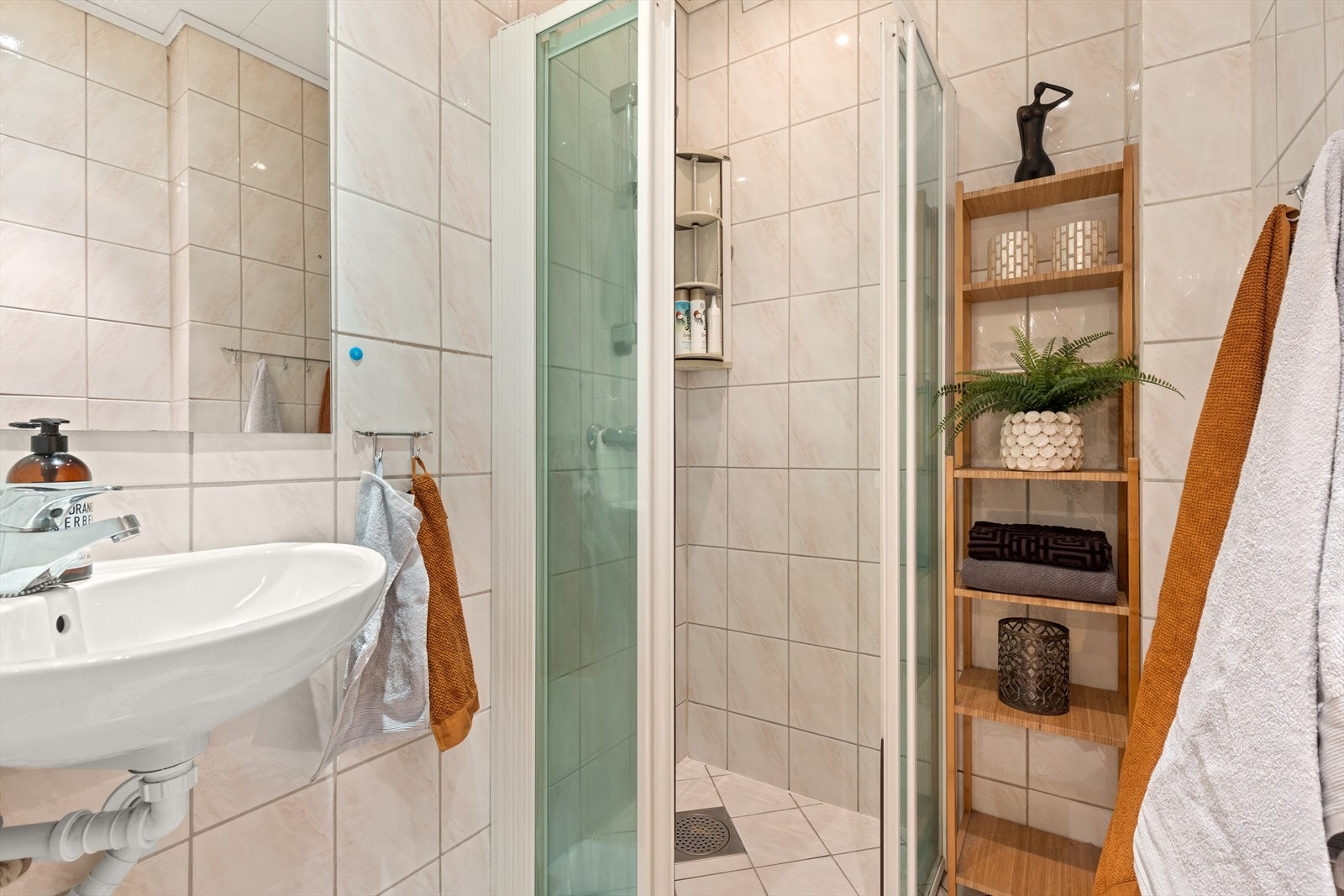 Flislagt baderom innredet med dusjhjørne med termostatbatteri og dusjvegger i herdet glass og helstøpt servant med ett-greps bl.batteri. Downlights i himling. Galleribilde