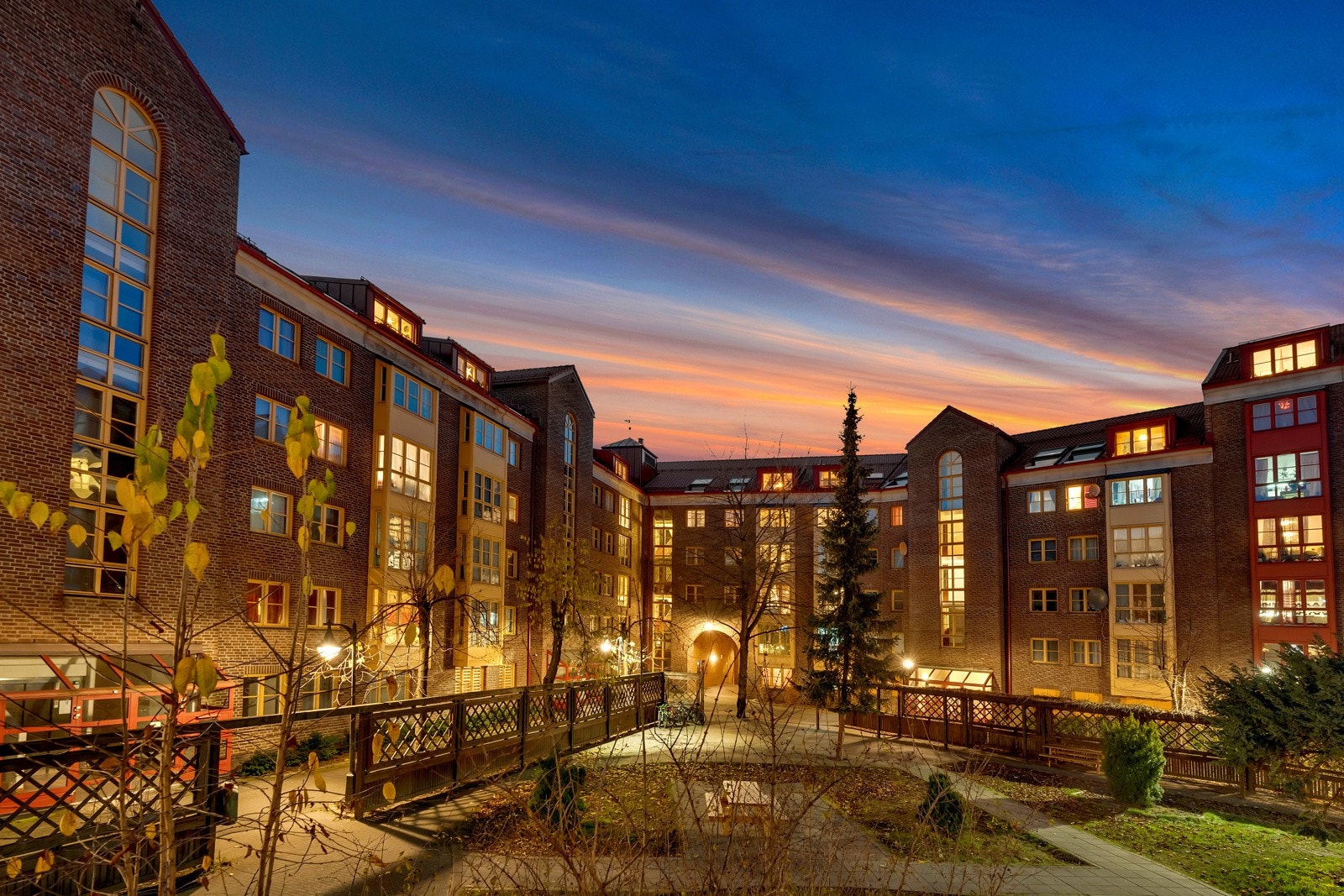 Fellesarealene er godt skjermet mellom byggene og pent opparbeidet med grønt gress, hekker, trær og bed med variert beplanting Galleribilde