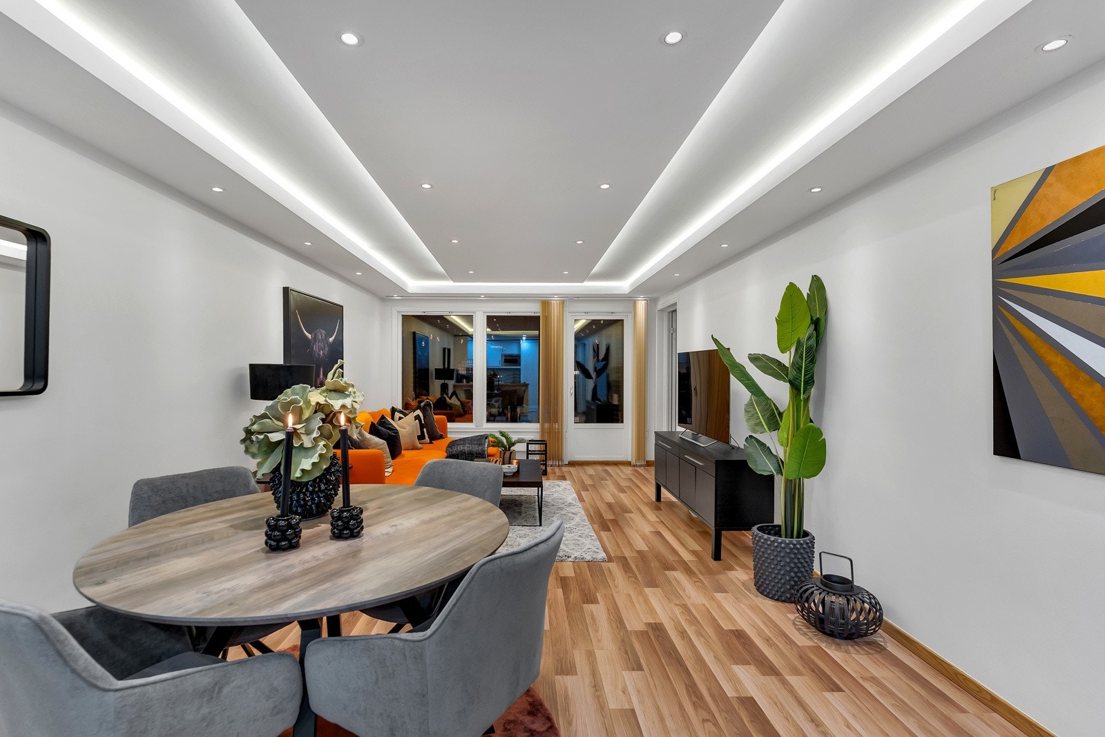 Stuen har nøttefarget laminatgulv, hvitmalte vegger og god plass til flere sittegrupper. På endeveggen er det vinduer og en glassdør som vender ut mot terrassen Galleribilde