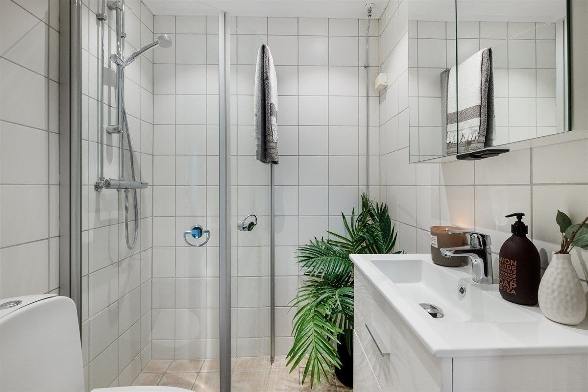 Bad med vegghengt servant og skap, dusjhjørne og vegghengt toalett. Bilde tatt fra tidligere. Inkluderer også kombinert vaskemaskin med tørketrommel. Galleribilde