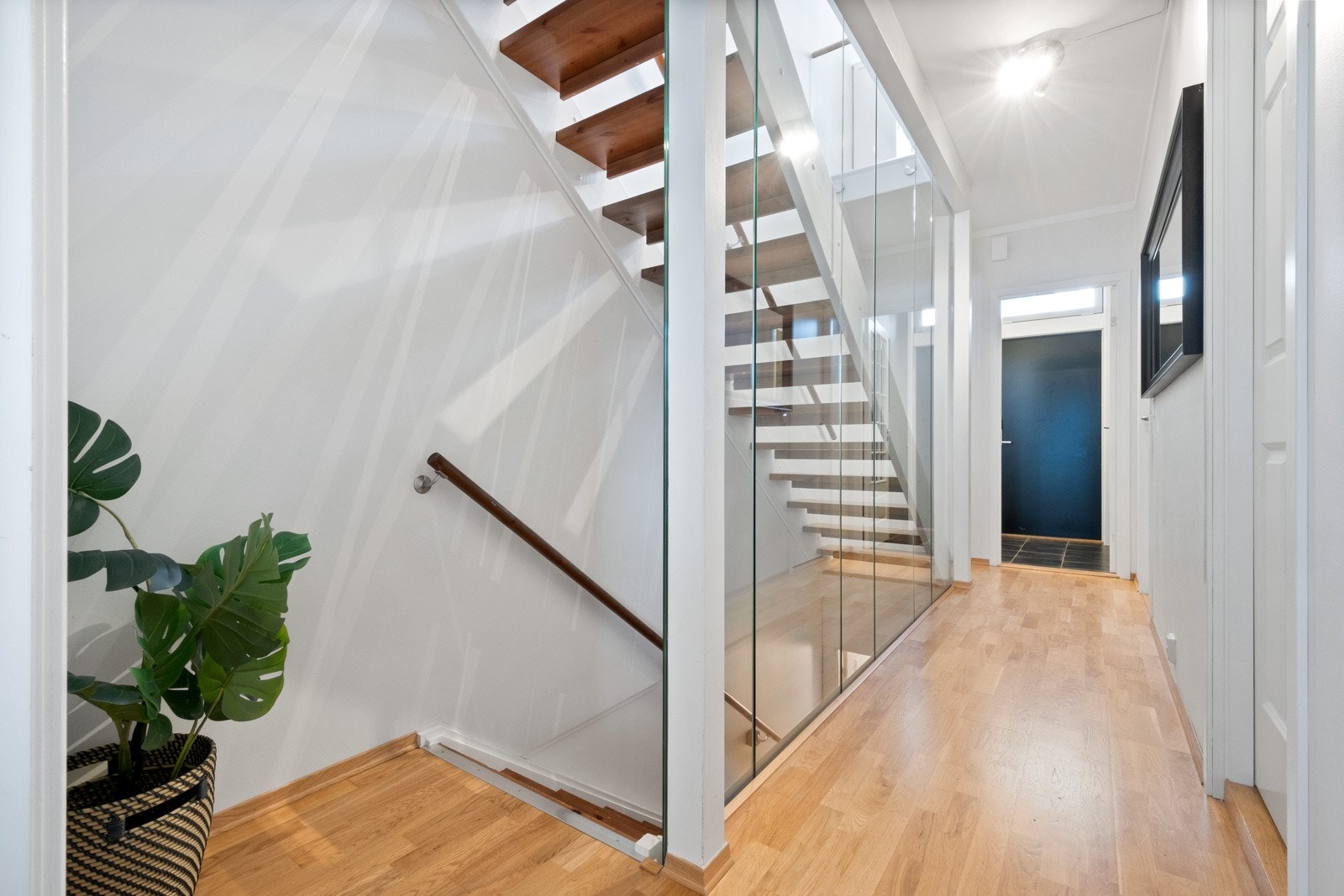 Videre inn kommer man til en gang med flott og trendy glassvegg. Gangen fordeler seg til 2 soverom, baderom og trapperom til kjelleretasje og 2. etasje. Galleribilde