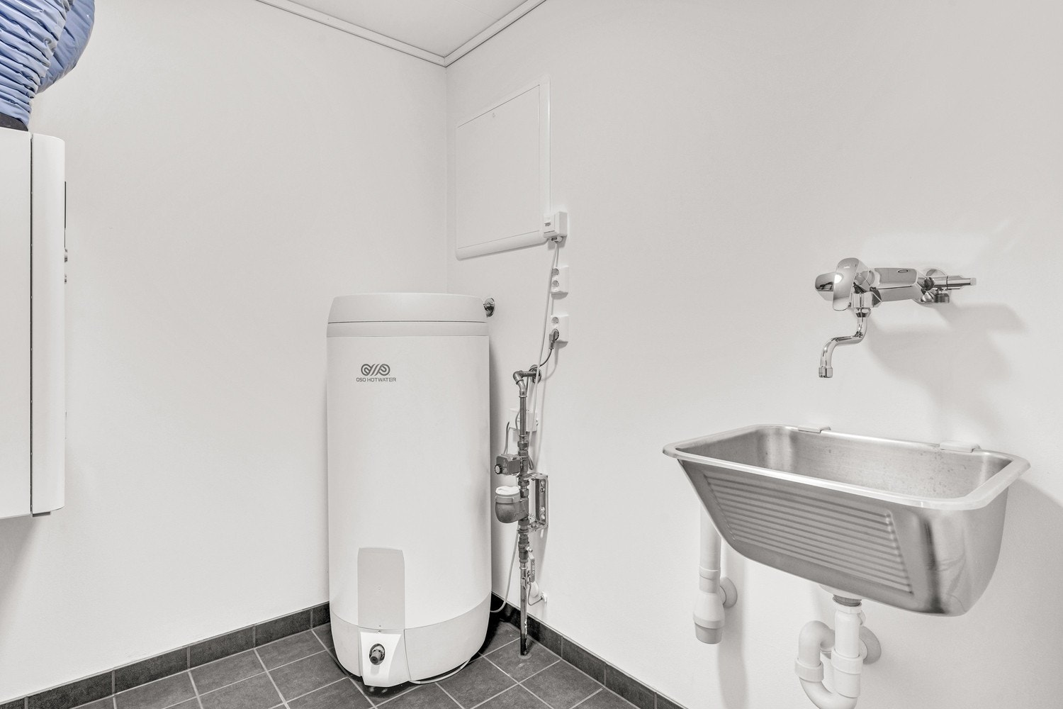 Vaskerommet/bod har flislagt gulv og opplegg for vaskemaskin. Bilde fra tilsvarende bolig. Galleribilde