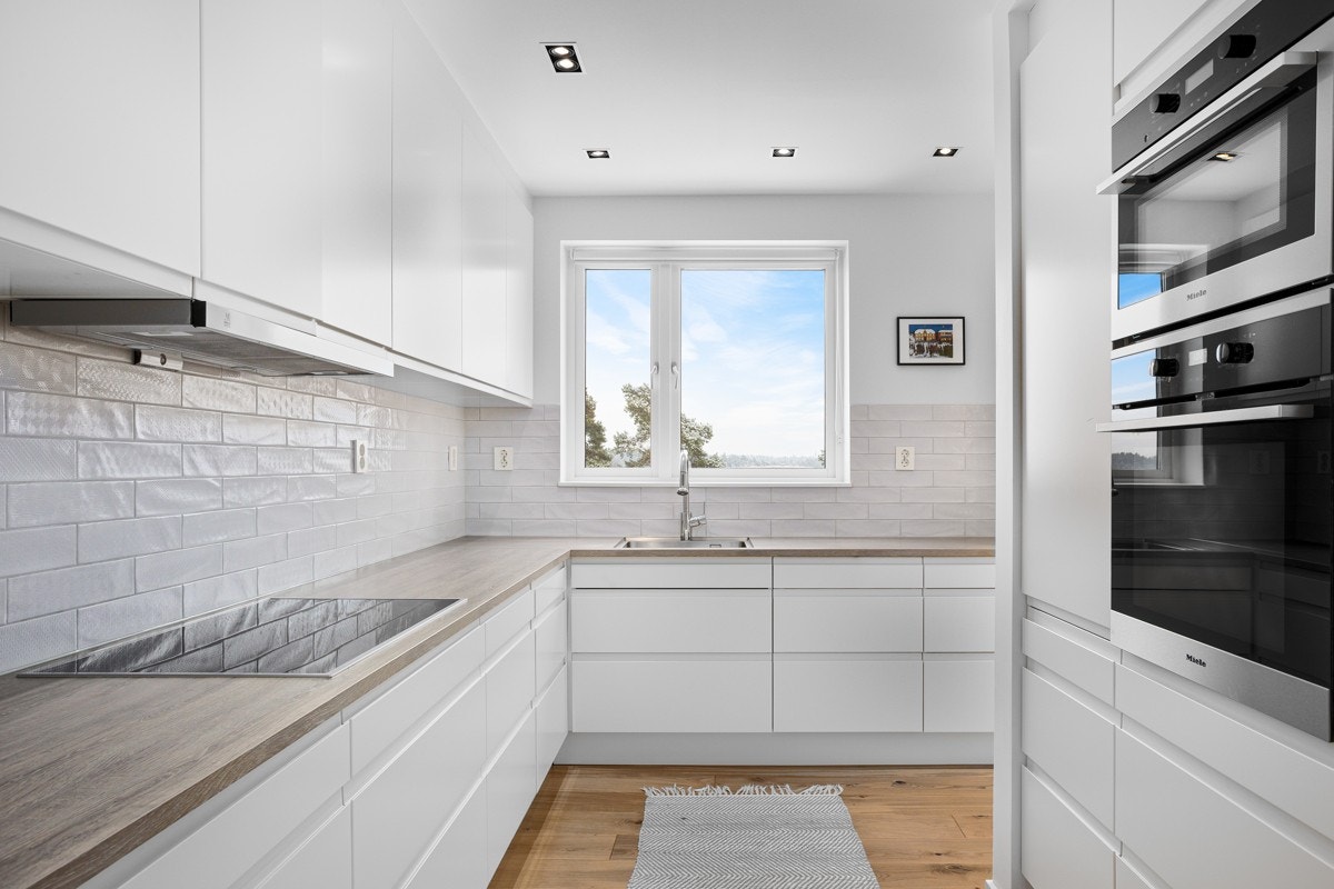 Det stilrene kjøkkenet ligger i første underetasje med glassdører inn fra både gang og stue. Galleribilde